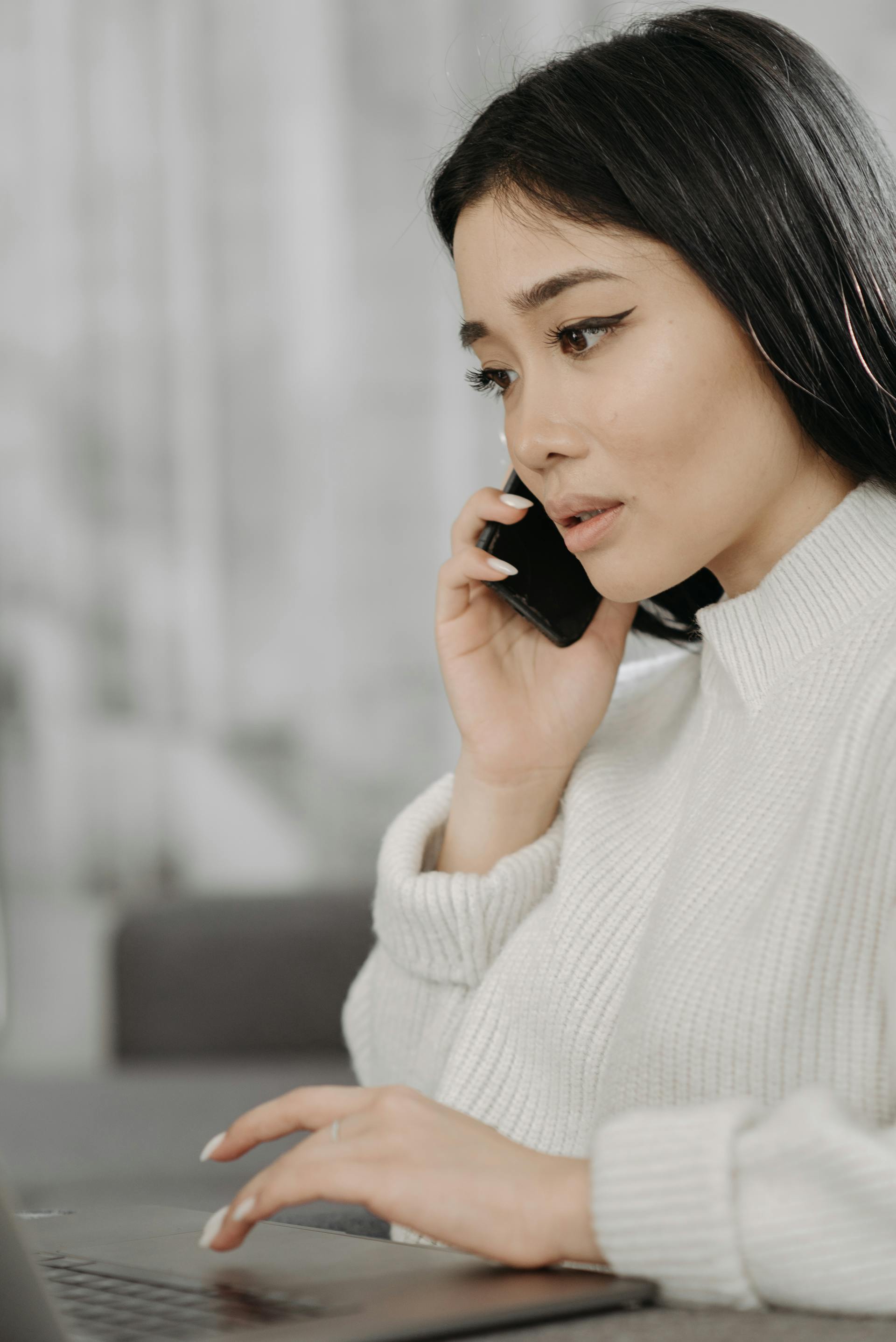 Une femme à l'expression triste parlant au téléphone tout en travaillant | Source : Pexels