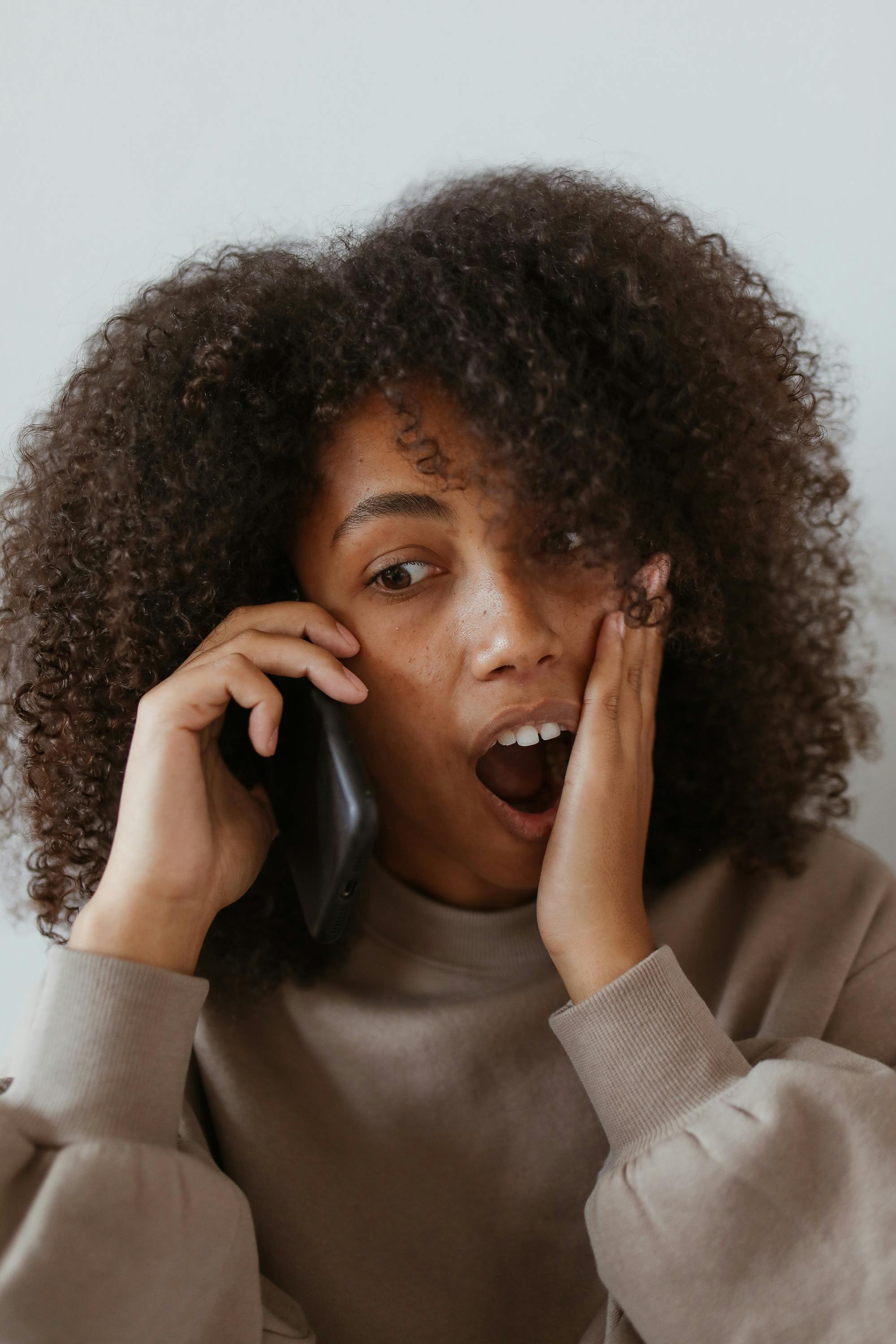 Une femme réagissant en état de choc tout en parlant au téléphone | Source : Pexels