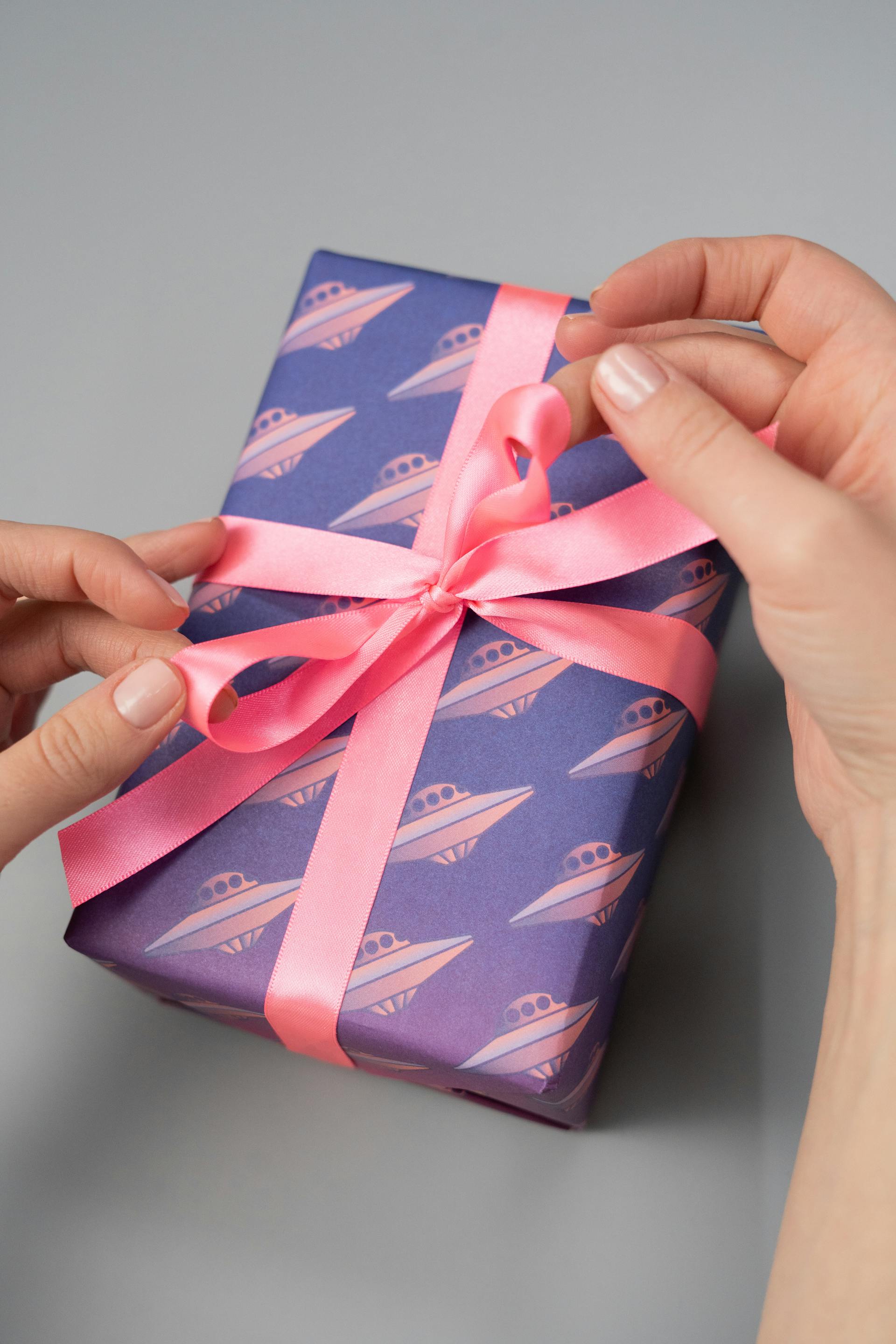 Gros plan d'une personne tenant un paquet cadeau avec un ruban rose | Source : Pexels