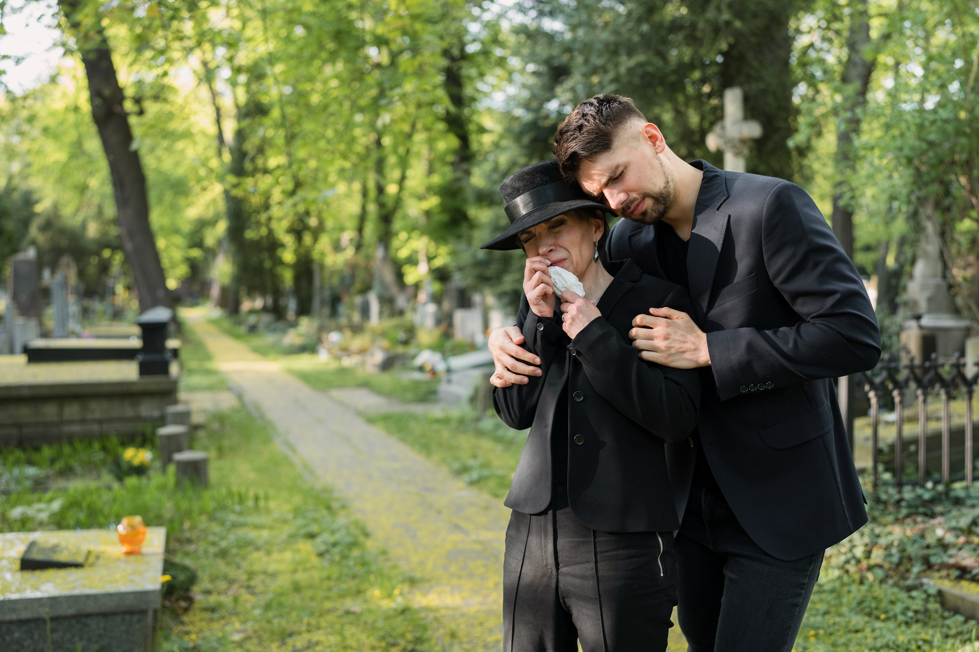 Un homme consolant une femme en deuil dans un cimetière | Source : Freepik