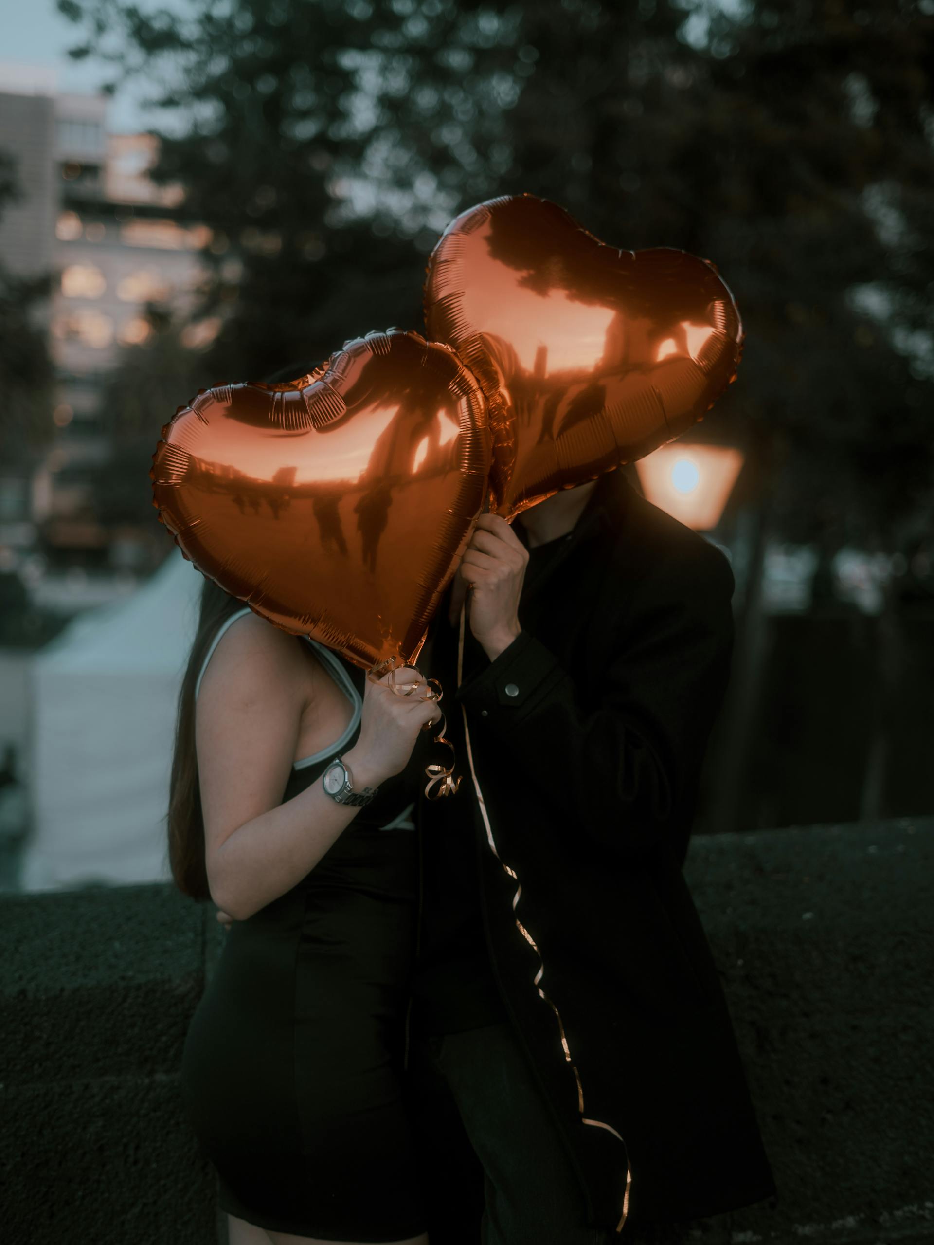 Un couple cache son visage avec des ballons en forme de cœur | Source : Pexels