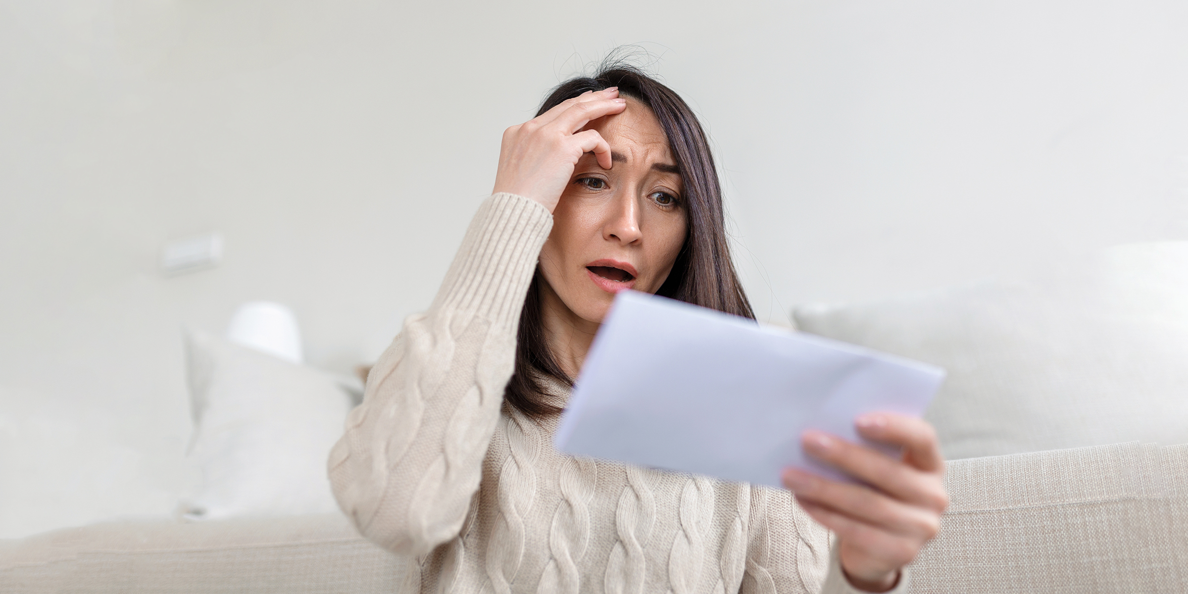 Une femme fixant une enveloppe en état de choc | Source : Shutterstock