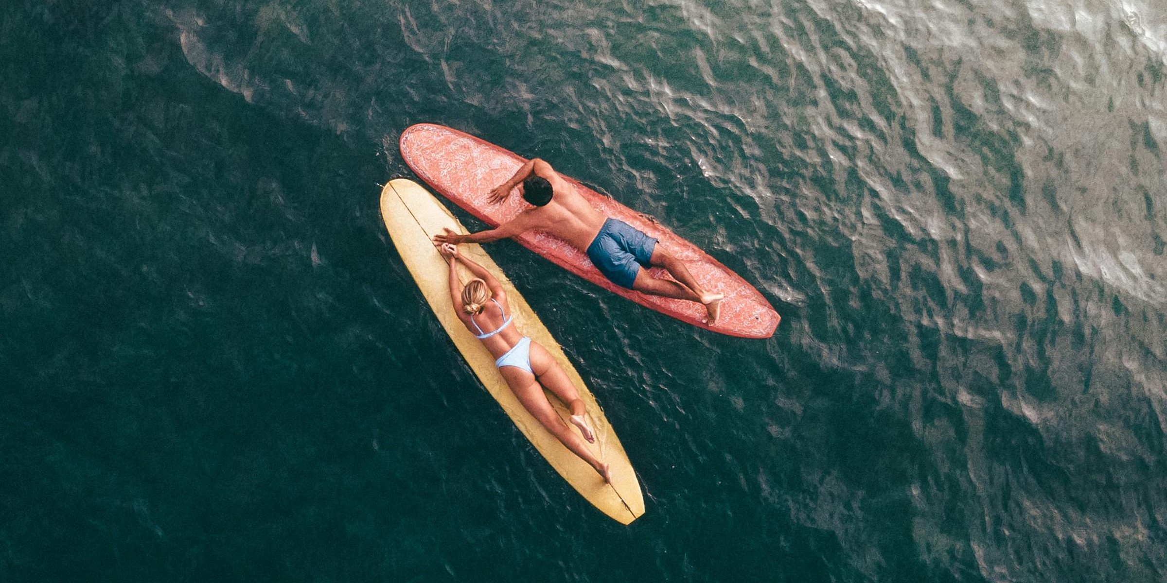 Un couple allongé sur des planches de surf. | Source : Pexels