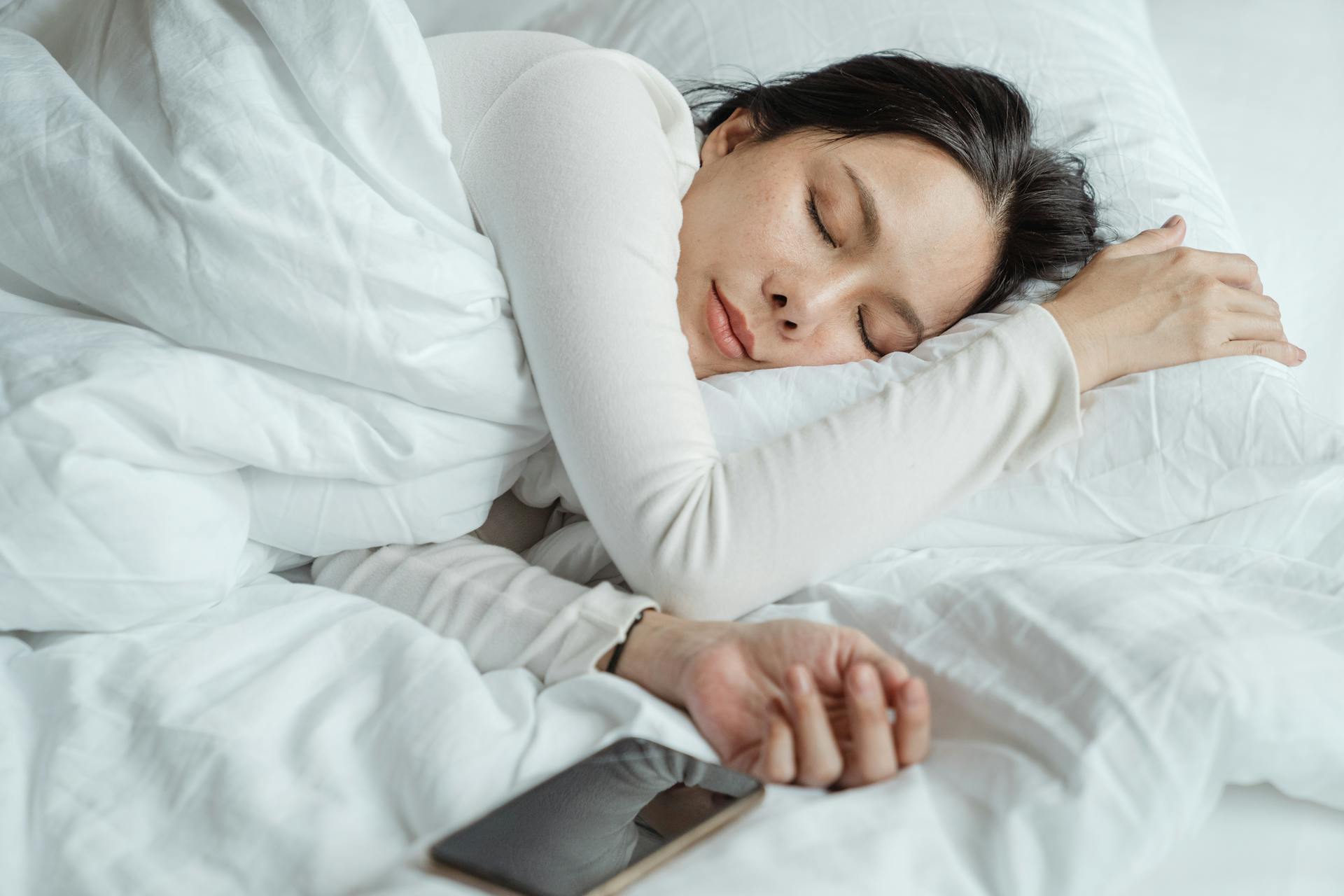 Une femme qui dort avec son téléphone à côté d'elle | Source : Pexels