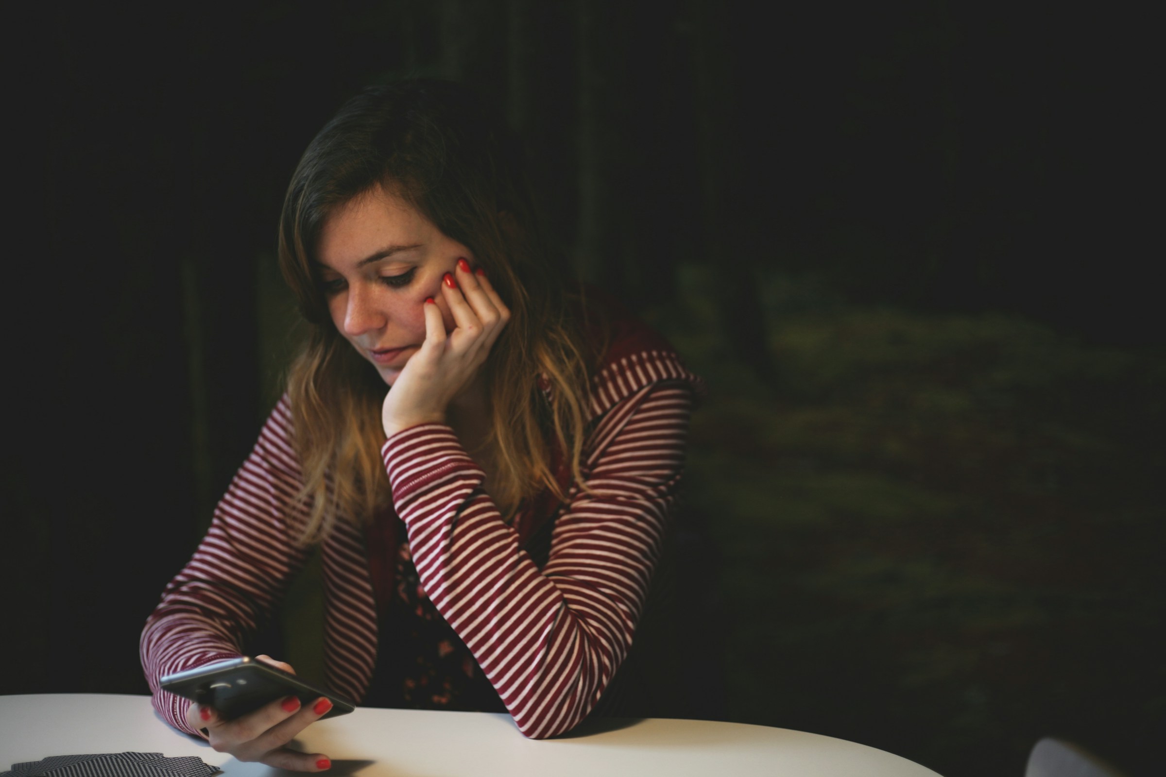 Jeune femme regardant pensivement son téléphone | Source : Unsplash