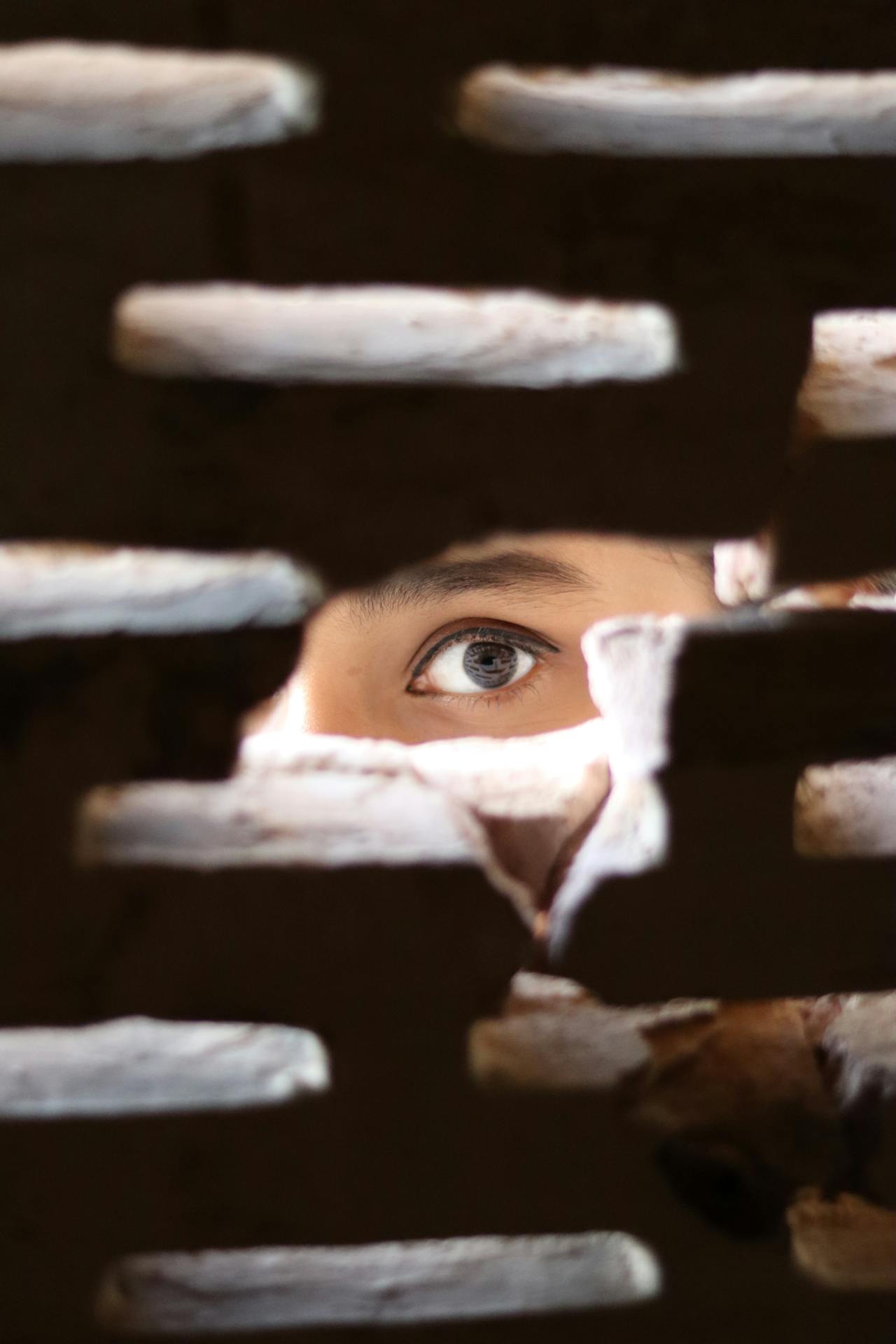 Une femme terrifiée qui jette un coup d'œil à travers un trou dans le mur | Source : Pexels