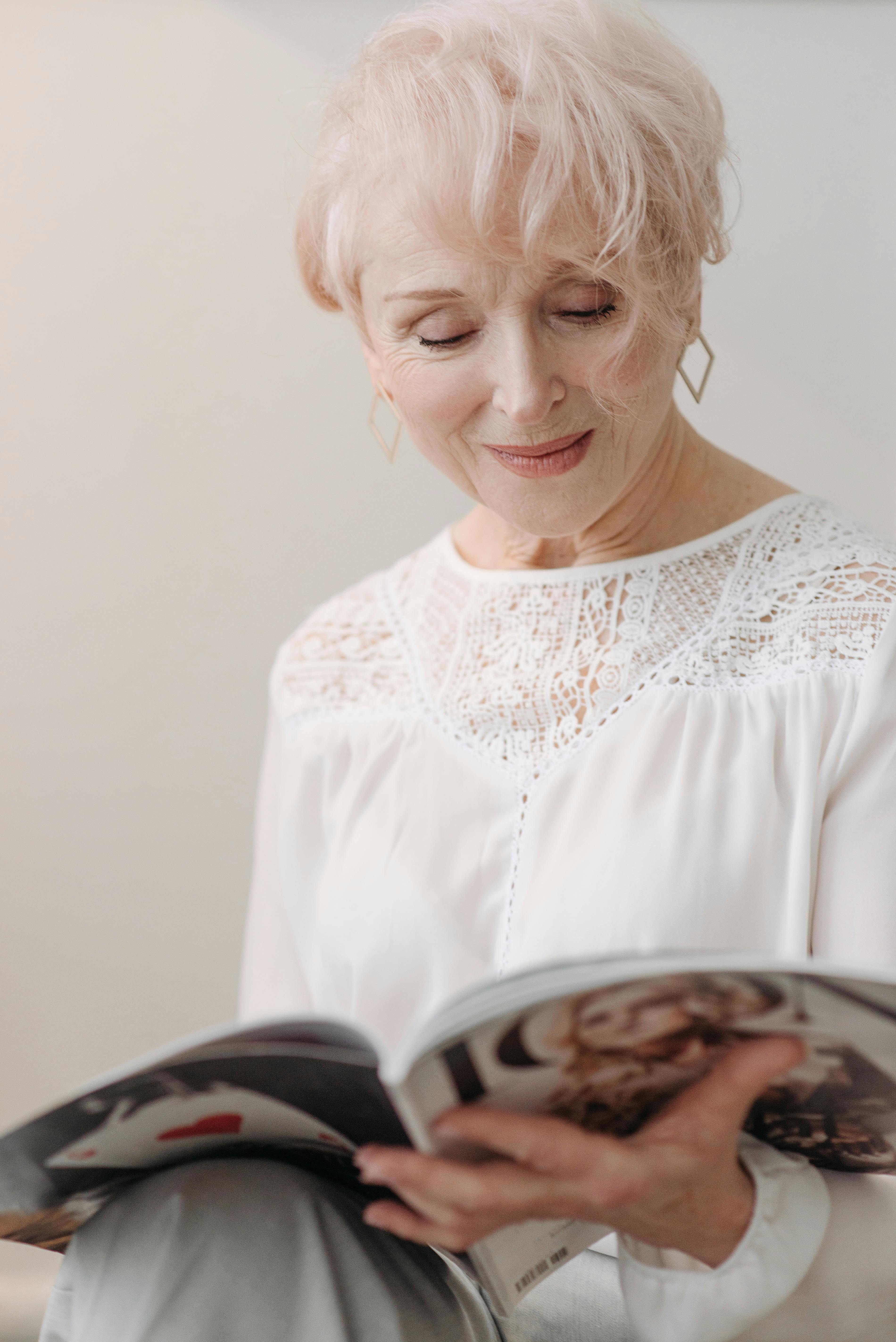 Une femme âgée souriante lisant un magazine | Source : Pexels