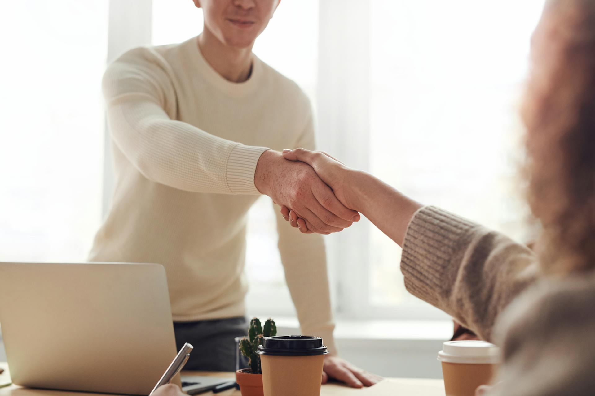 Une femme serrant la main d'un homme dans un bureau | Source : Pexels