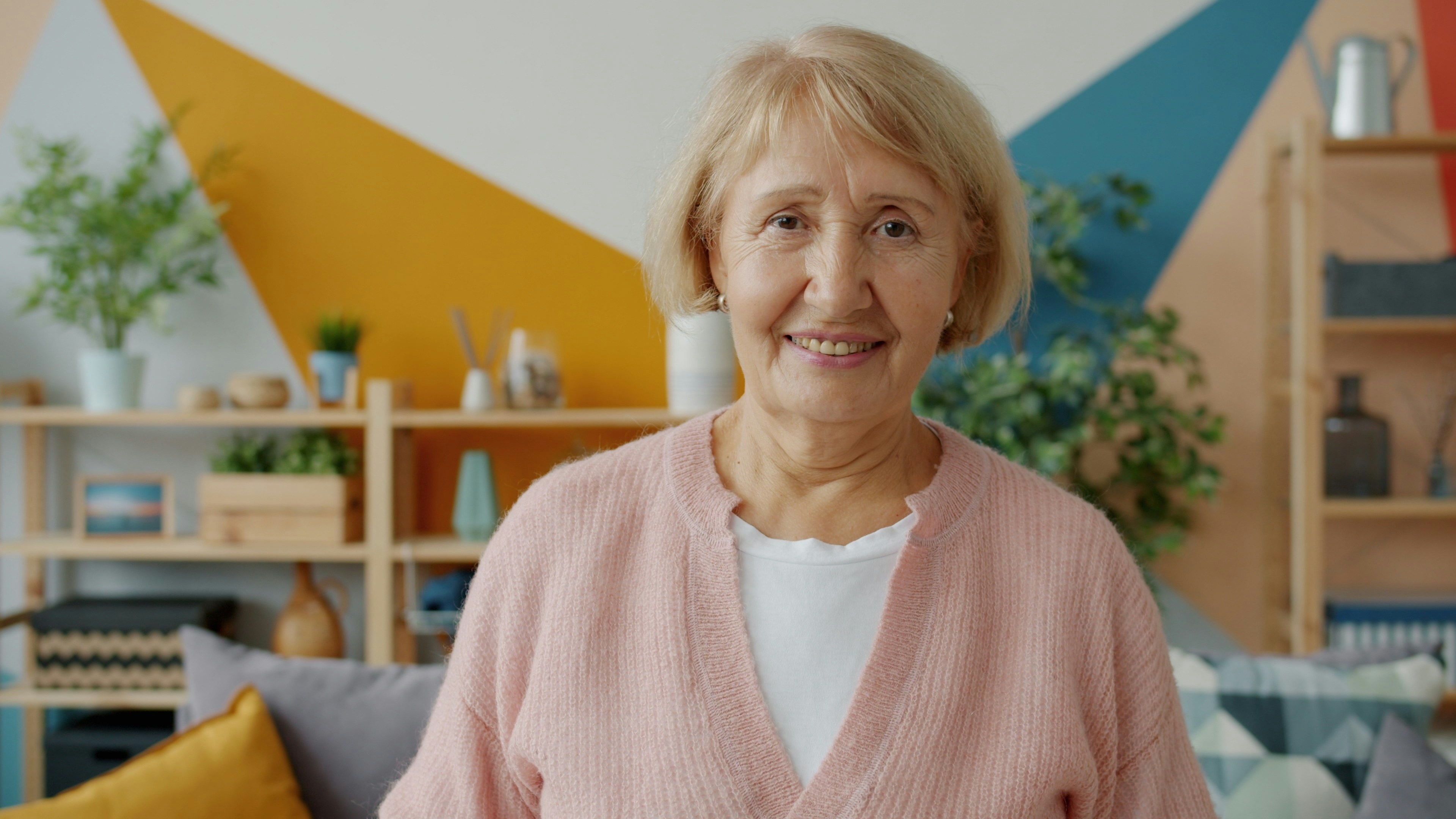 Une femme âgée souriante avec un cardigan rose | Source : Unsplash