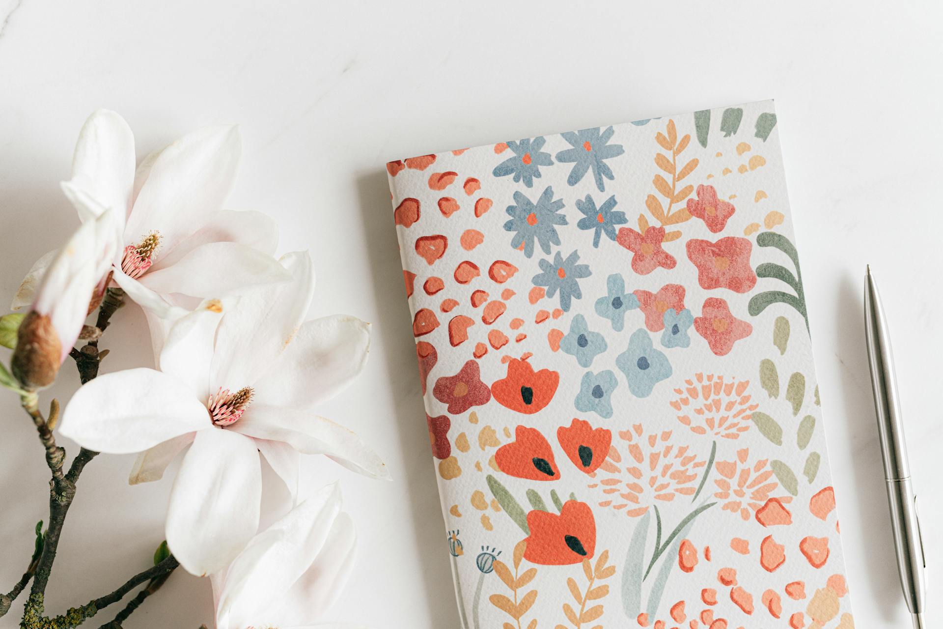 Un agenda et un stylo posés près de fleurs blanches | Source : Pexels
