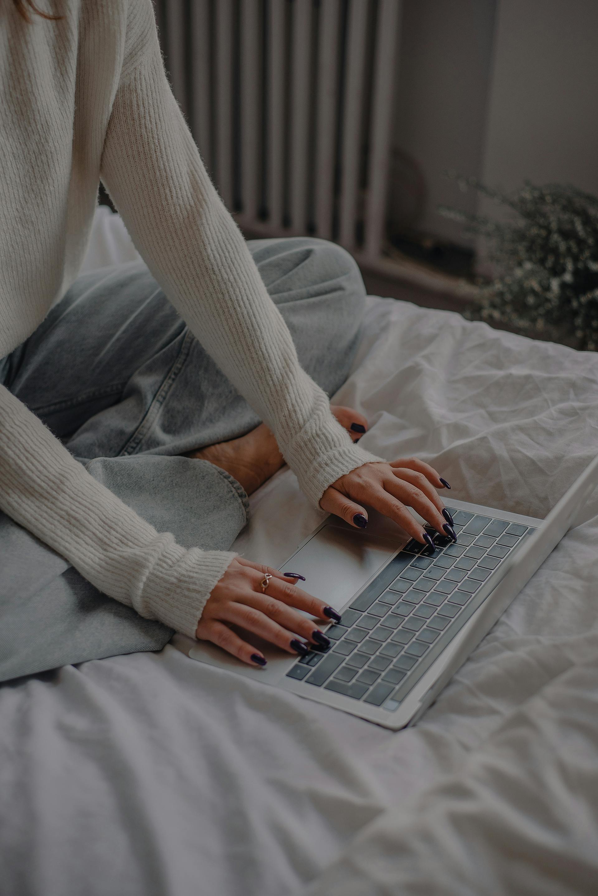 Gros plan sur une femme utilisant son ordinateur portable au lit | Source : Pexels