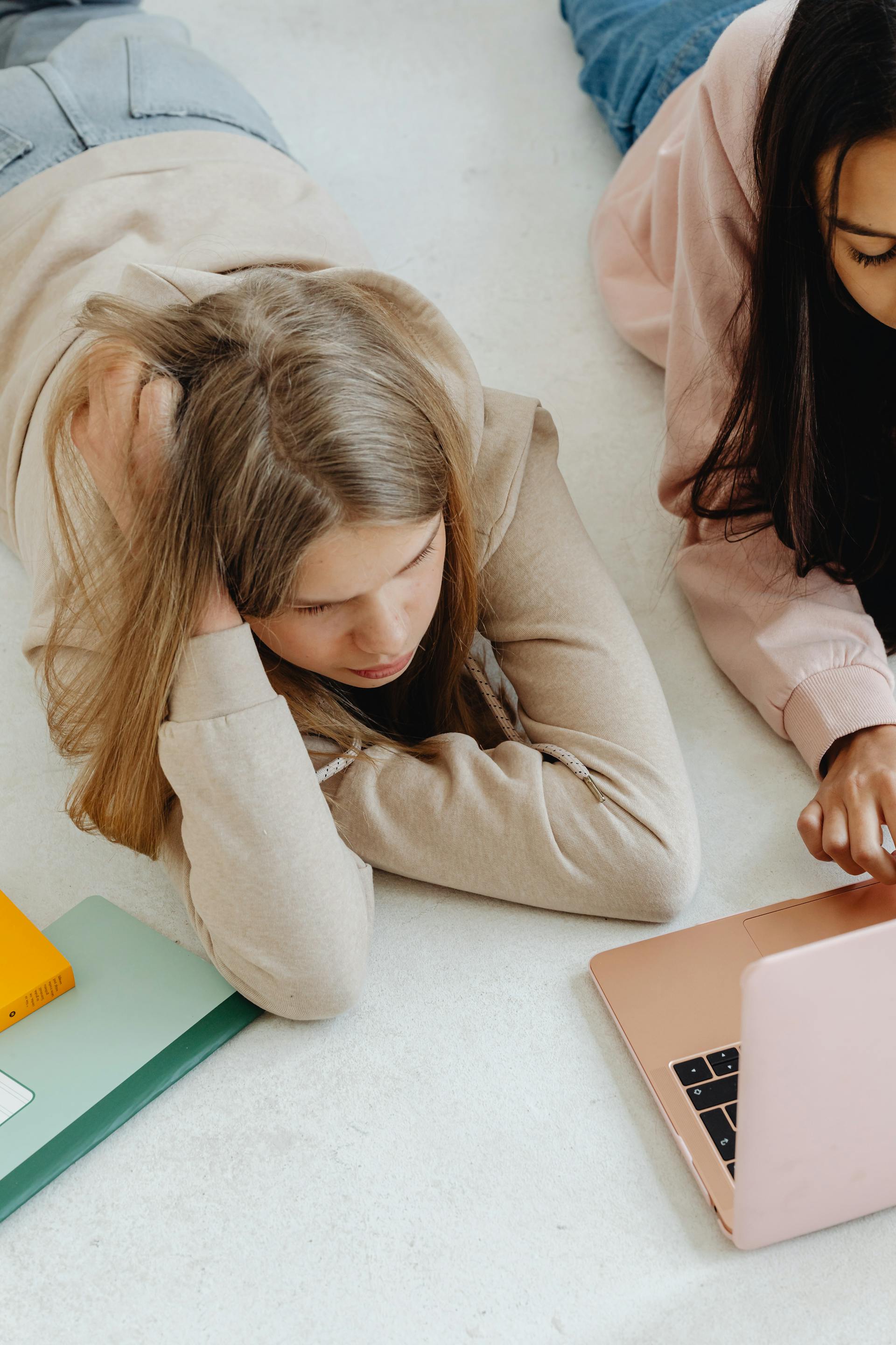 Deux adolescentes allongées ensemble sur le sol | Source : Pexels