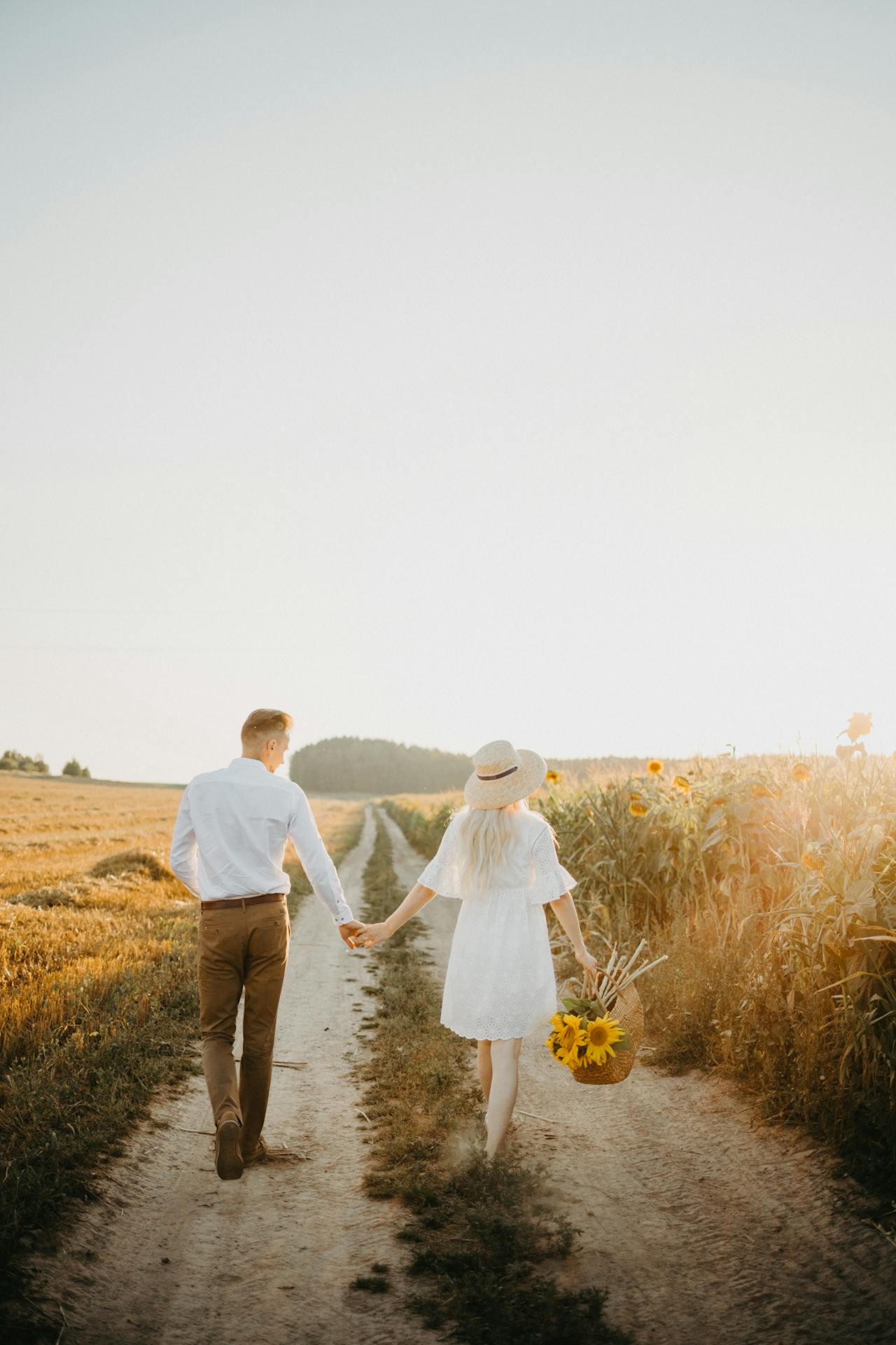 Une femme tenant un panier de tournesols et marchant avec un homme | Source : Pexels