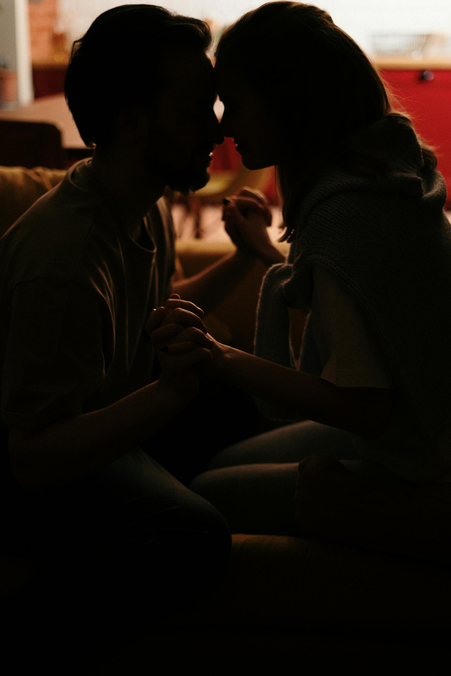 Un couple se tenant par la main tout en étant assis sur le canapé | Source : Pexels