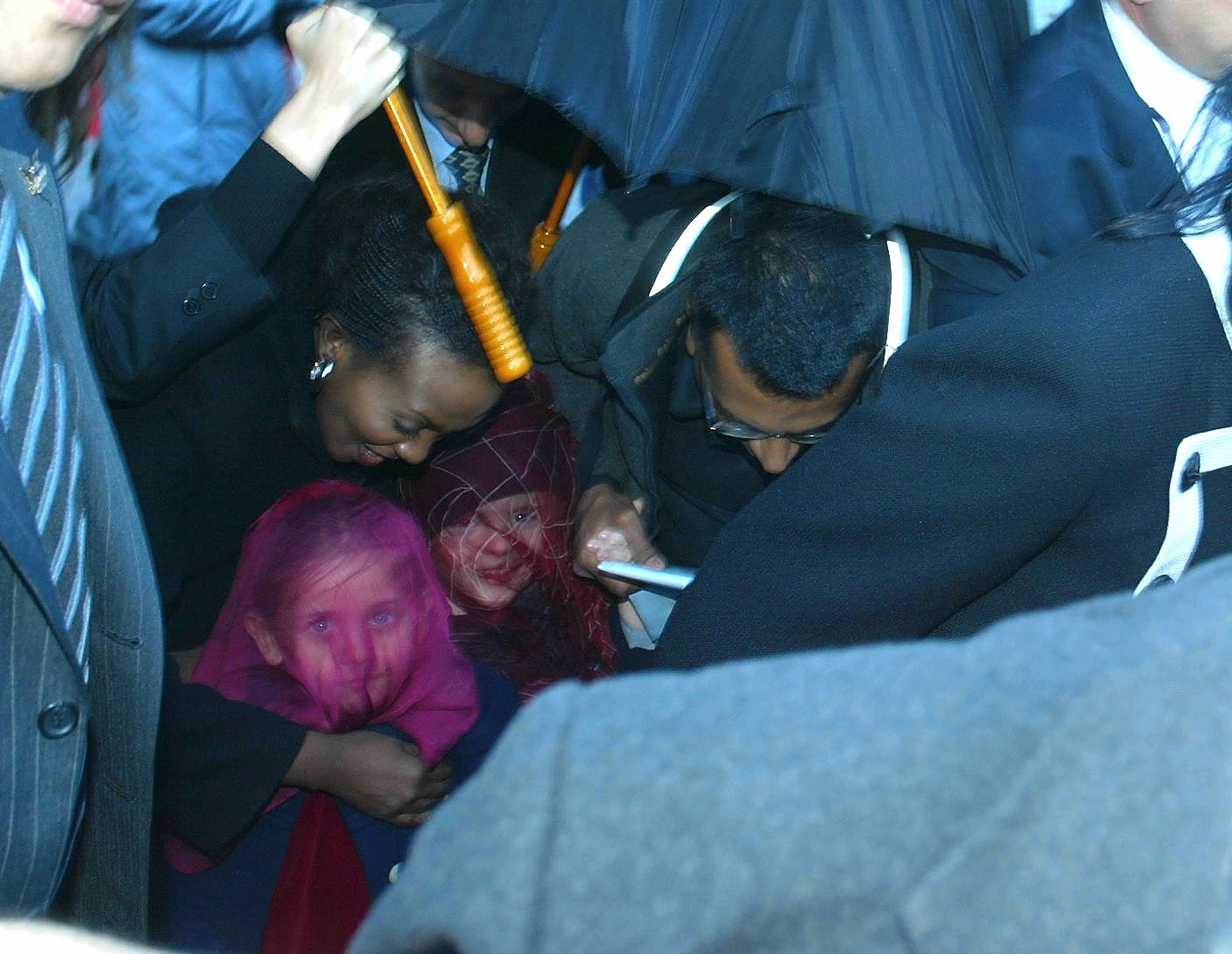 Des gardes du corps escortent les enfants de Michael Jackson, dont la jeune Paris Jackson, lors d'une visite au zoo de Berlin le 20 novembre 2002. Les enfants, dont les visages sont voilés pour préserver leur intimité, ont attiré l'attention du monde entier, l'icône de la pop cherchant à les protéger des regards du public lors de ses voyages à l'étranger.