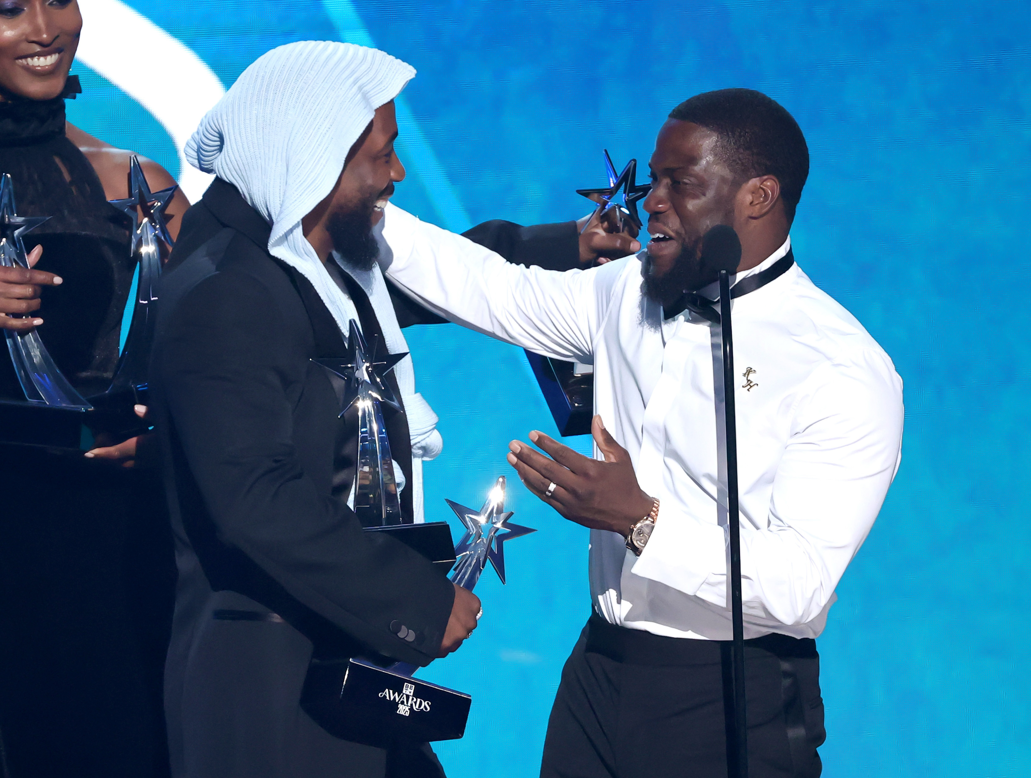 Kevin Hart partage un rire avec Kendrick Lamar tout en remettant l'un des nombreux prix de l'artiste lors d'un échange ludique sur la scène des BET Awards 2025. Les mains de Lamar étaient déjà pleines de trophées à ce stade du spectacle.