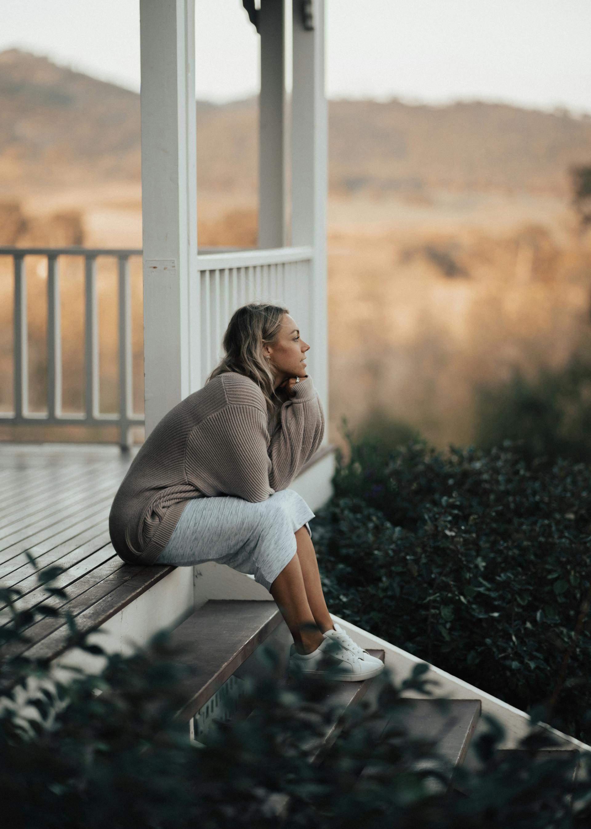 Une femme assise sur le porche de sa maison | Source : Pexels