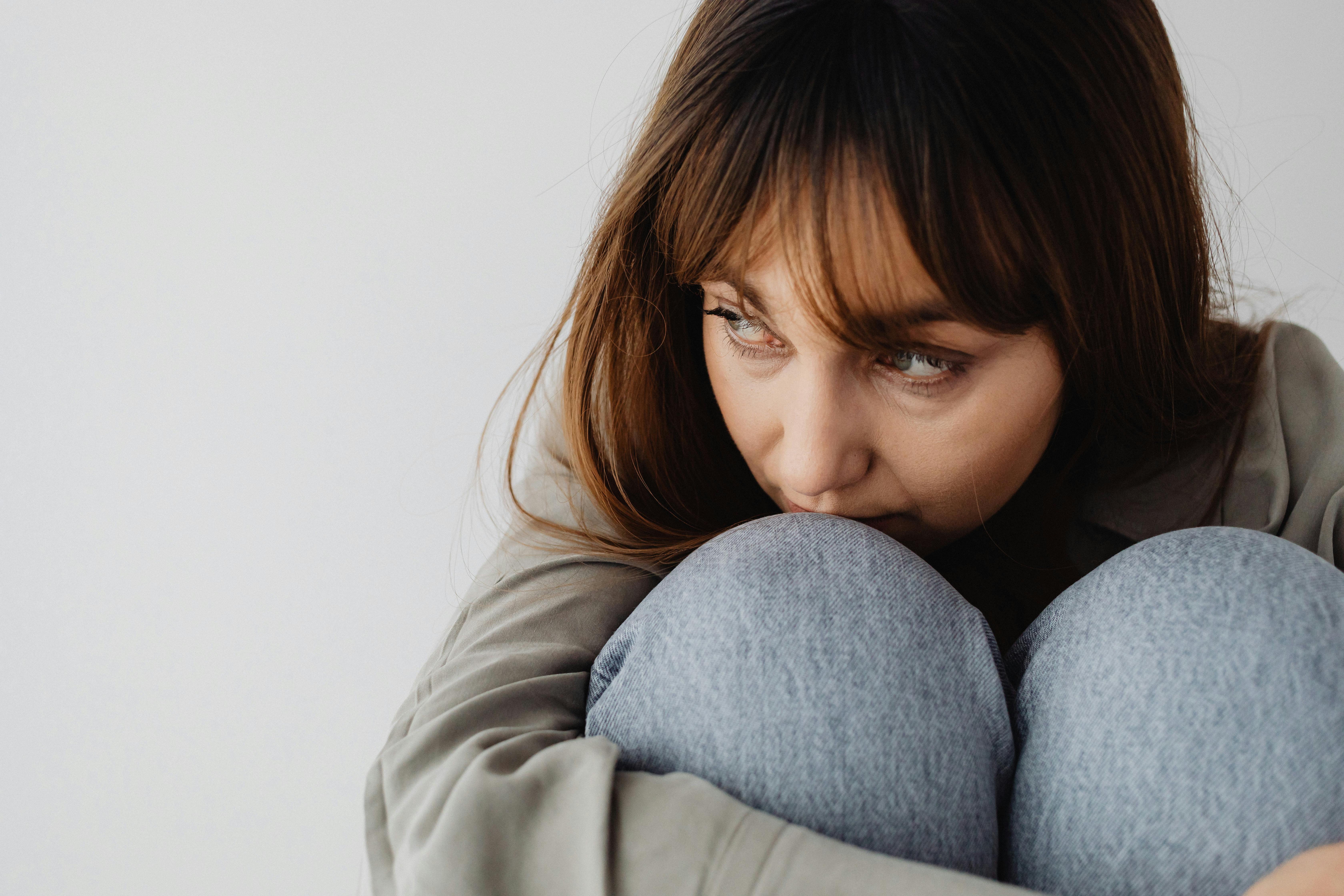 Une femme triste et sérieuse serrant ses genoux dans ses bras | Source : Pexels