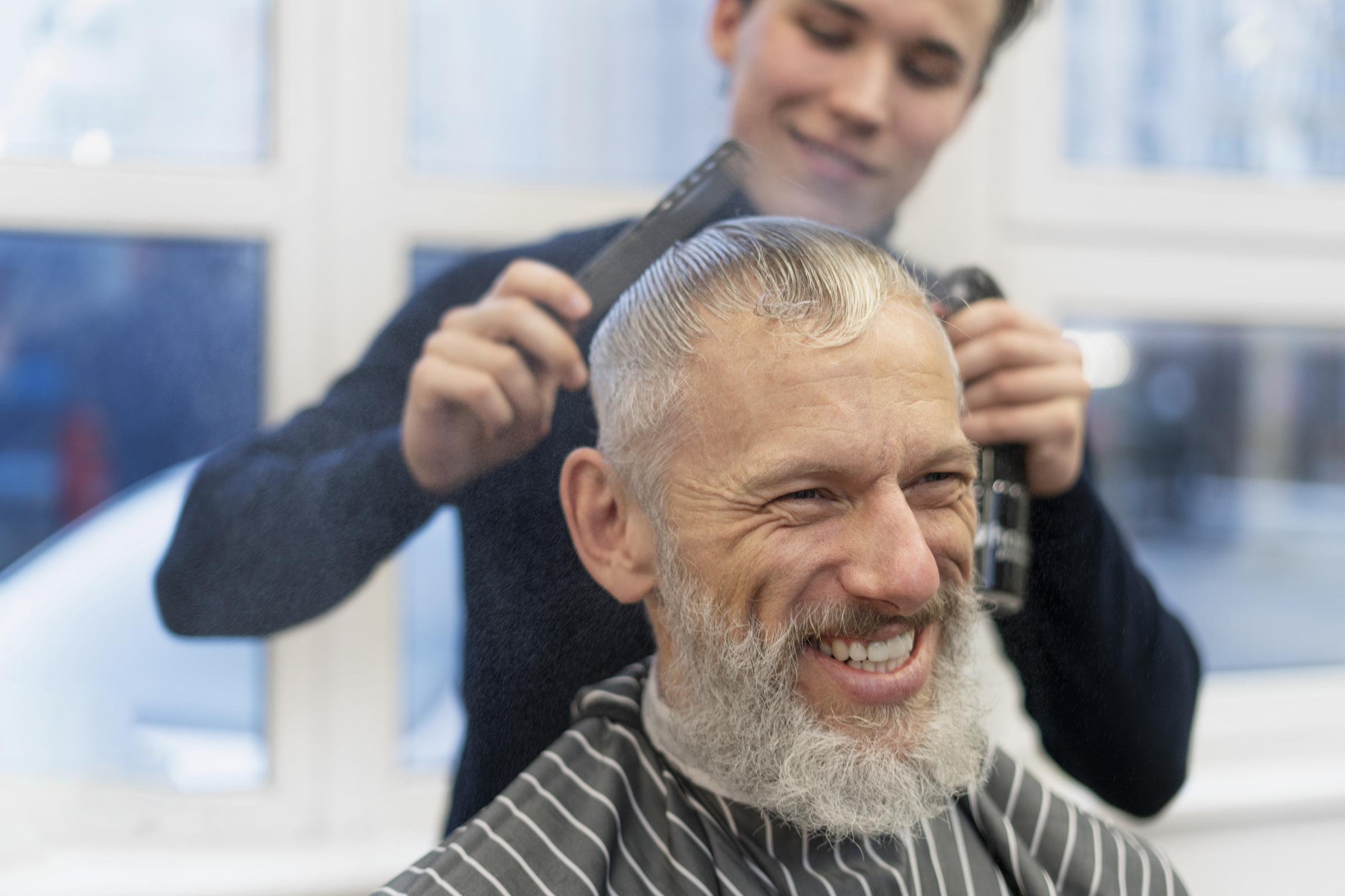 Un homme souriant dans un salon de coiffure | Source : Freepik