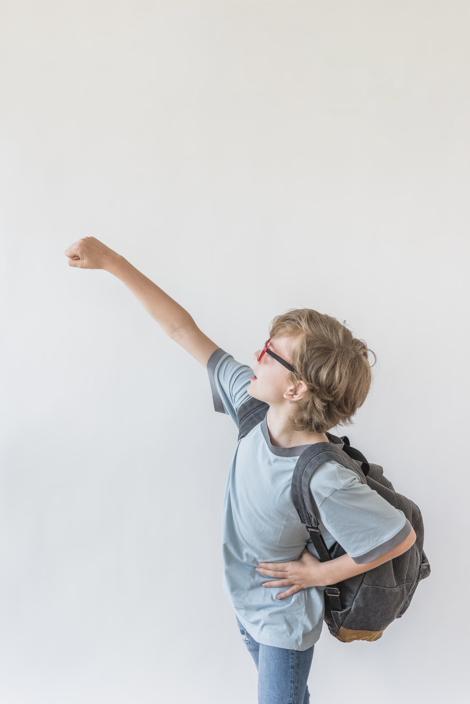Vue de côté d'un jeune garçon avec son sac à dos | Source : Freepik