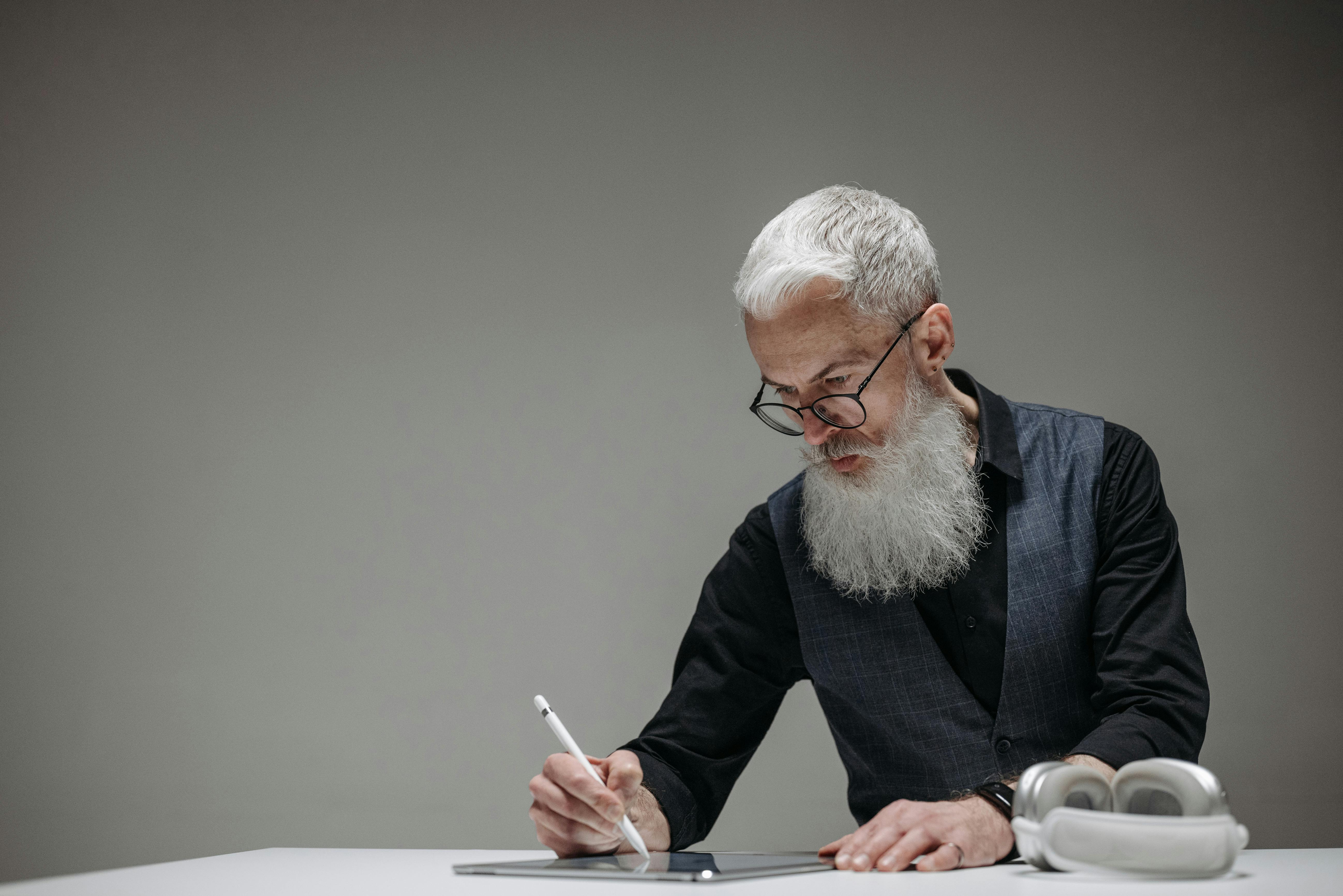 Homme barbu utilisant un stylet léger sur une tablette | Source : Pexels