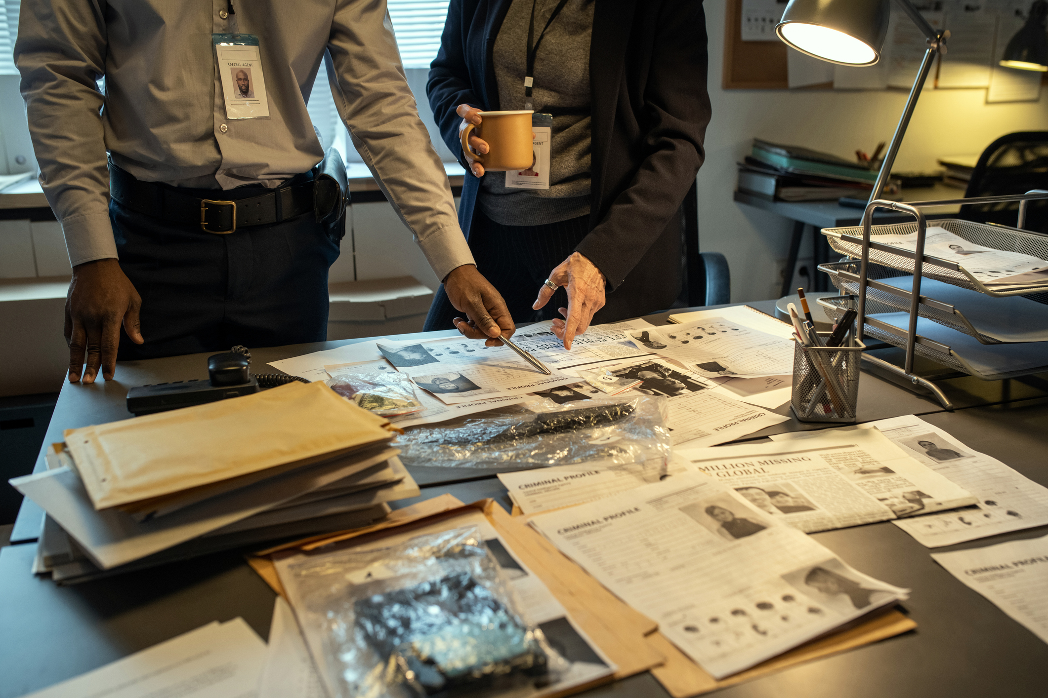 Deux agents interraciaux du FBI montrant des informations personnelles sur un chef de gang tout en discutant de profils criminels dans le cadre d'une enquête I Photo d'illustration I Source : Getty Images