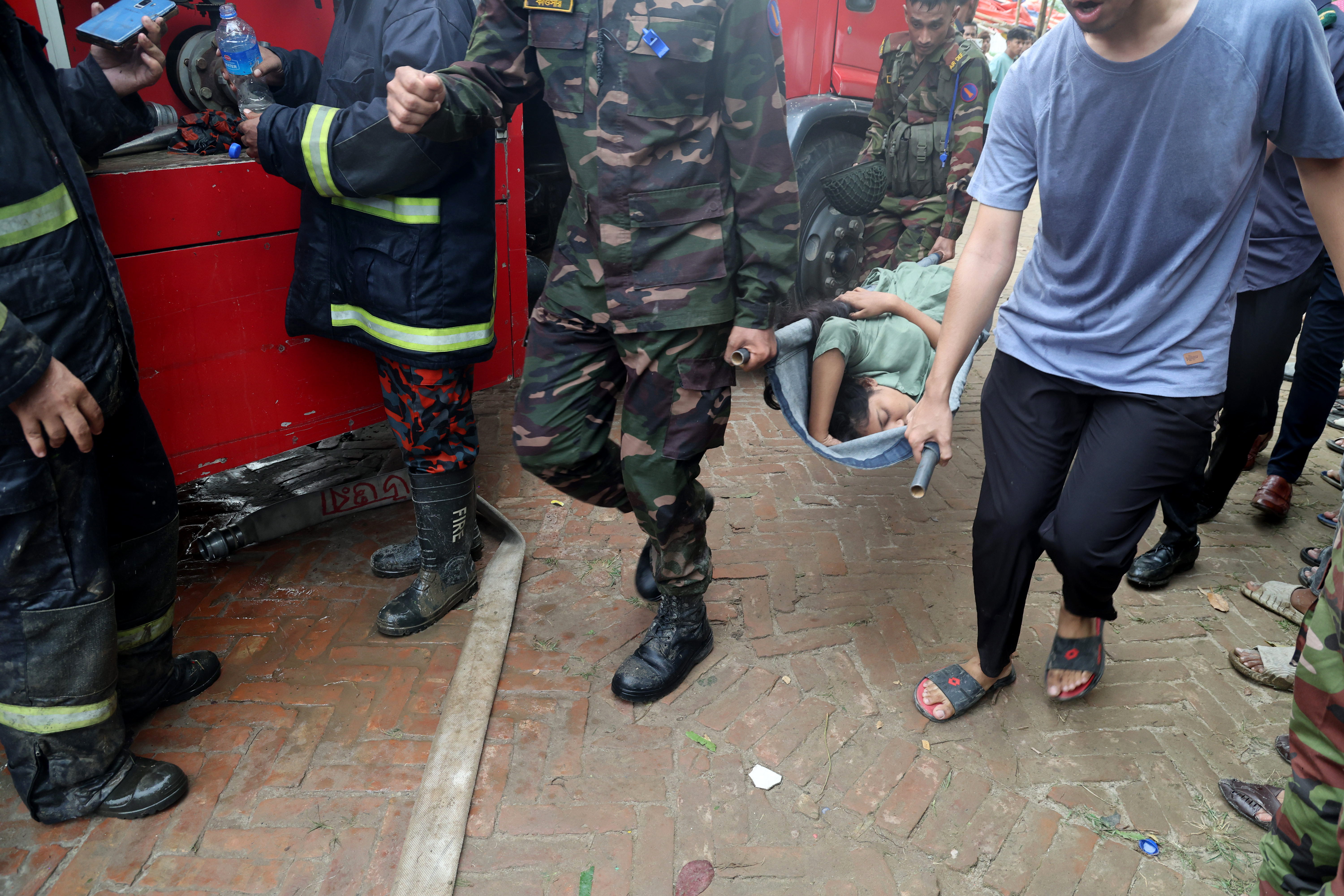 Une personne transportée par des membres de l'armée bangladaise et des pompiers après que l'avion F7 de l'armée de l'air bangladaise s'est écrasé sur un bâtiment du Milestone College à Uttara, à Dhaka, vers 13h30, à Dhaka, au Bangladesh, le 21 juillet 2025 | Source : Getty Images