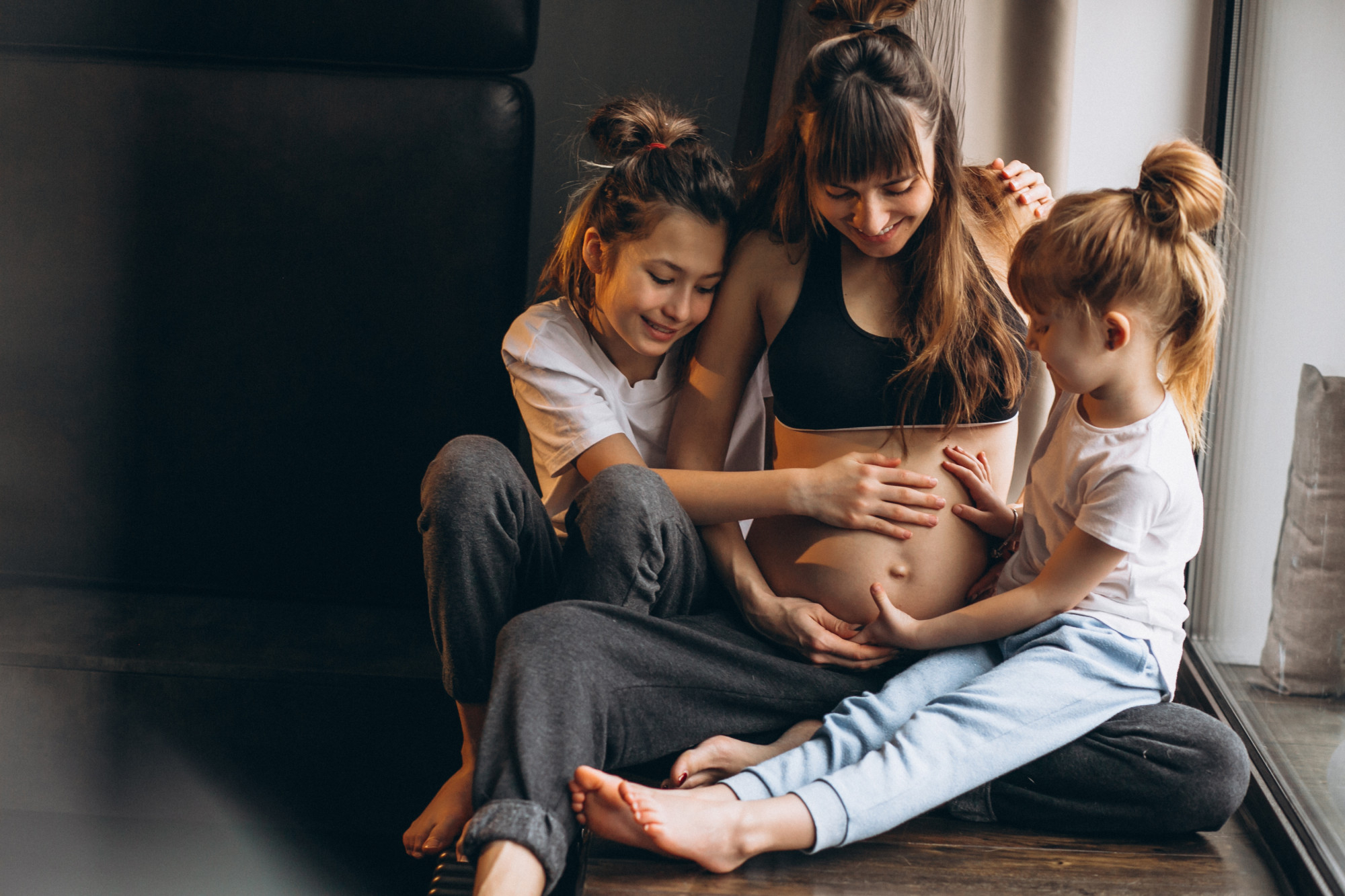 Une femme enceinte avec des enfants assis près de la fenêtre | Source : Freepik