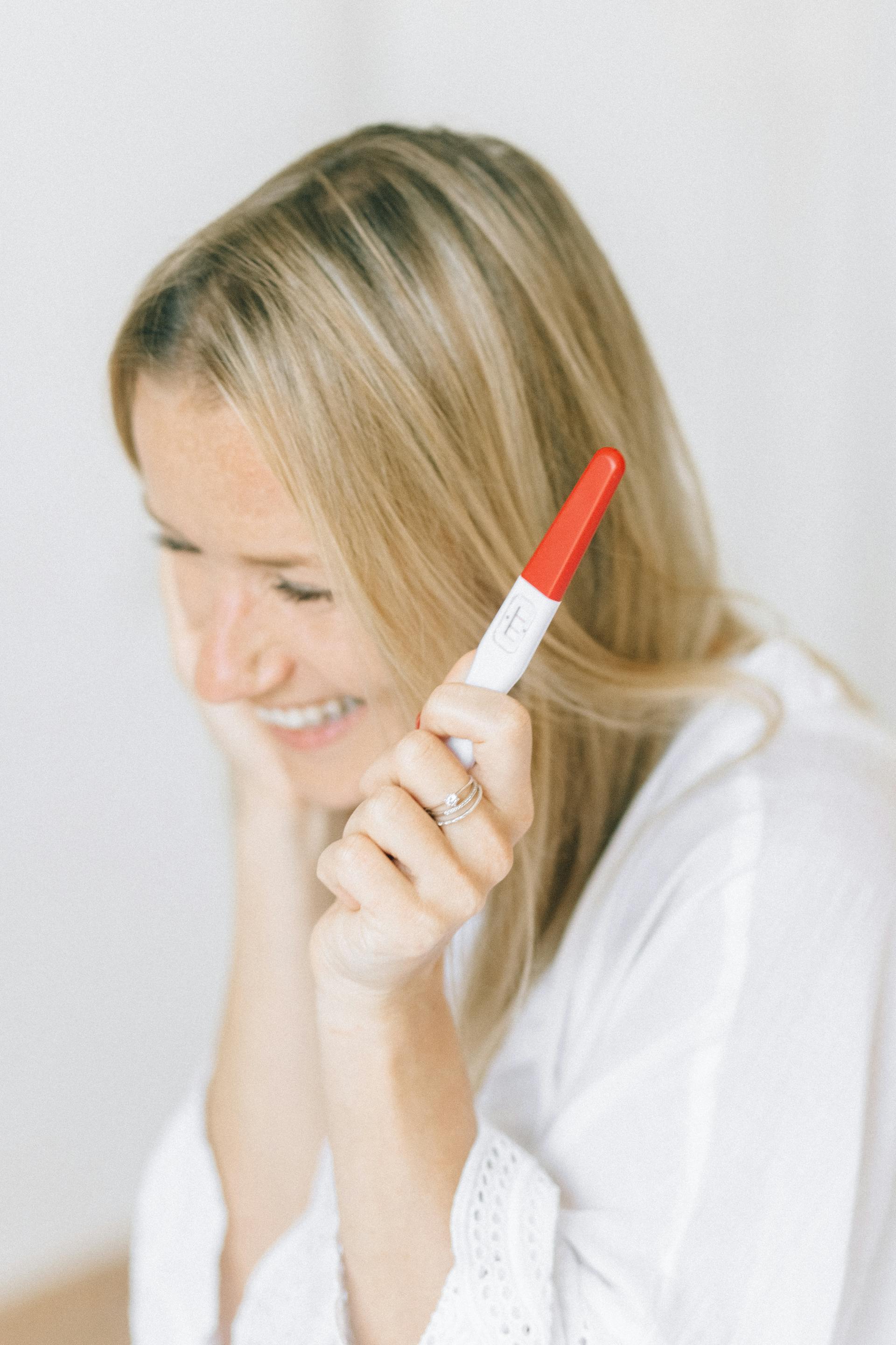 Une femme heureuse tenant un test de grossesse | Source : Pexels