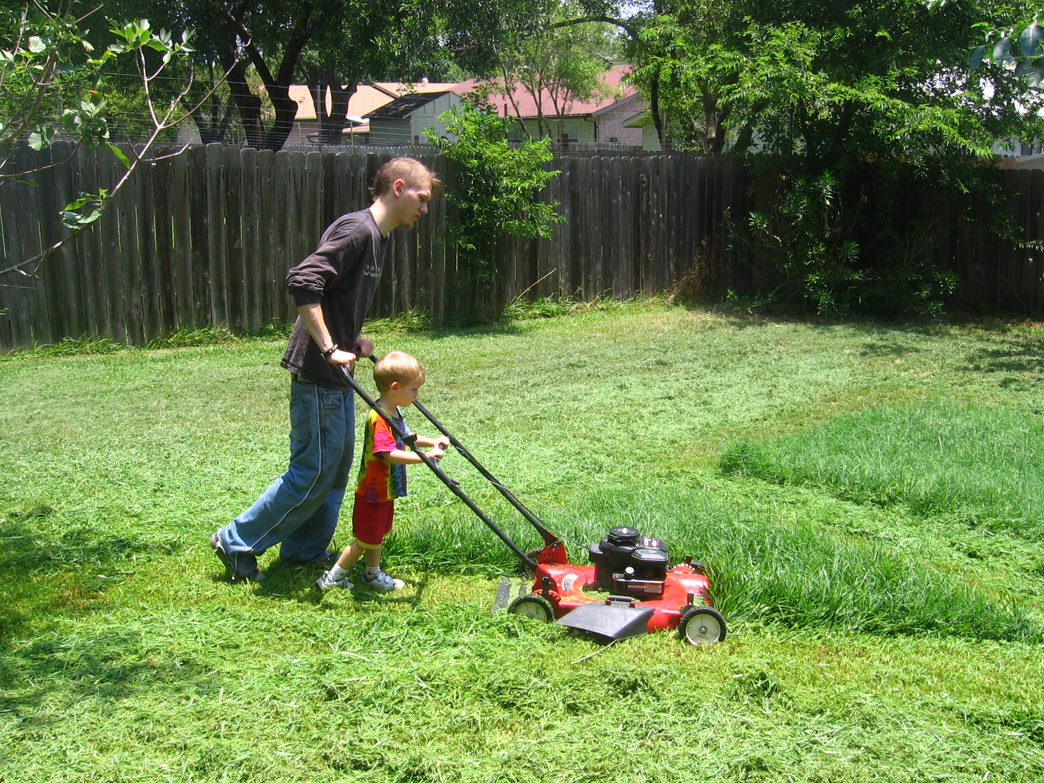 Un homme et son fils en train de tondre la pelouse | Source : Flickr