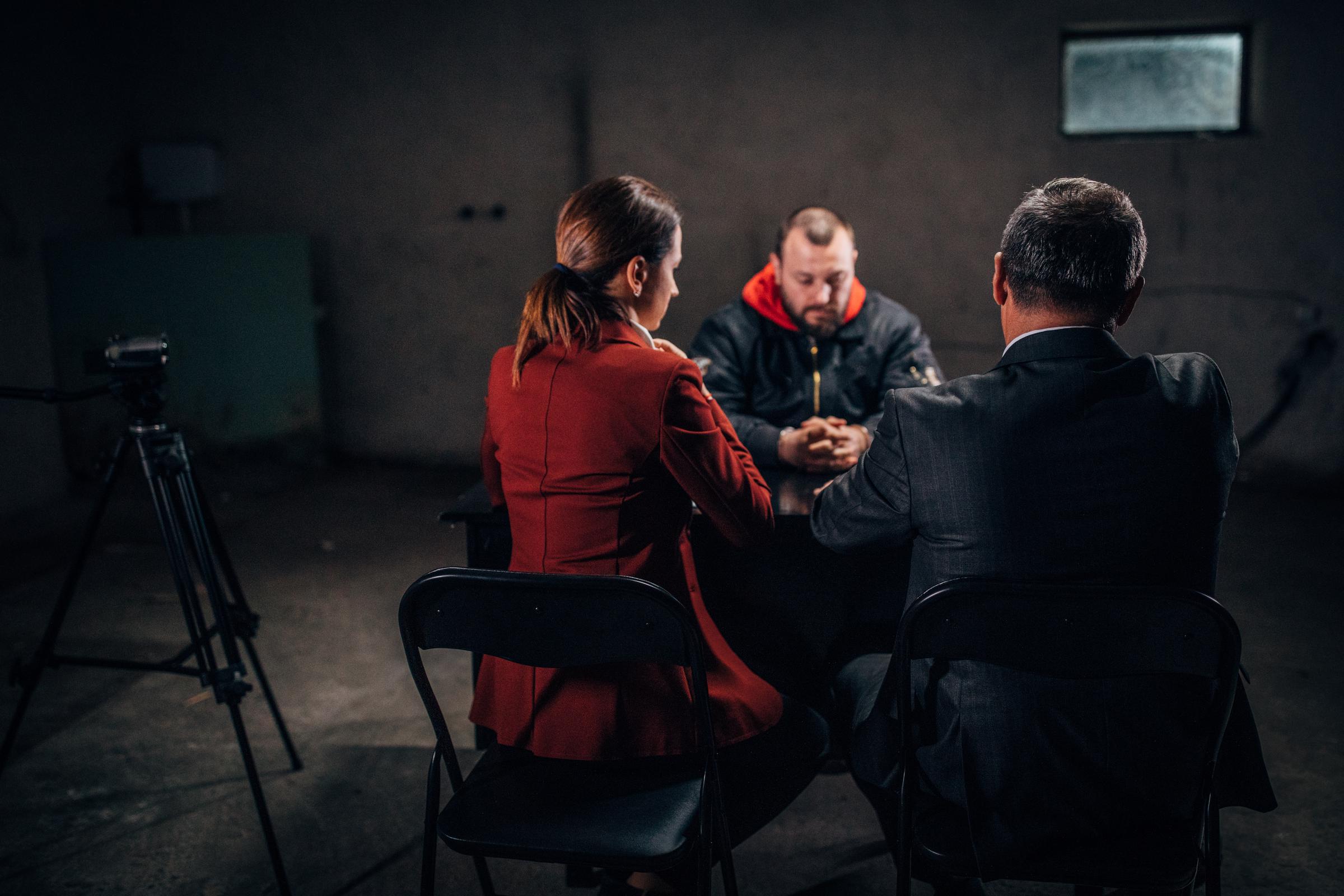 Un homme menotté et deux détectives | Source : Getty Images