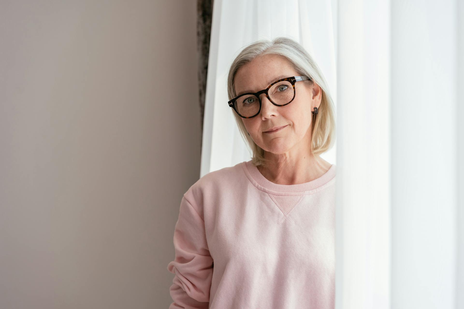 Une femme d'âge moyen avec un pull rose portant des lunettes | Source : Pexels