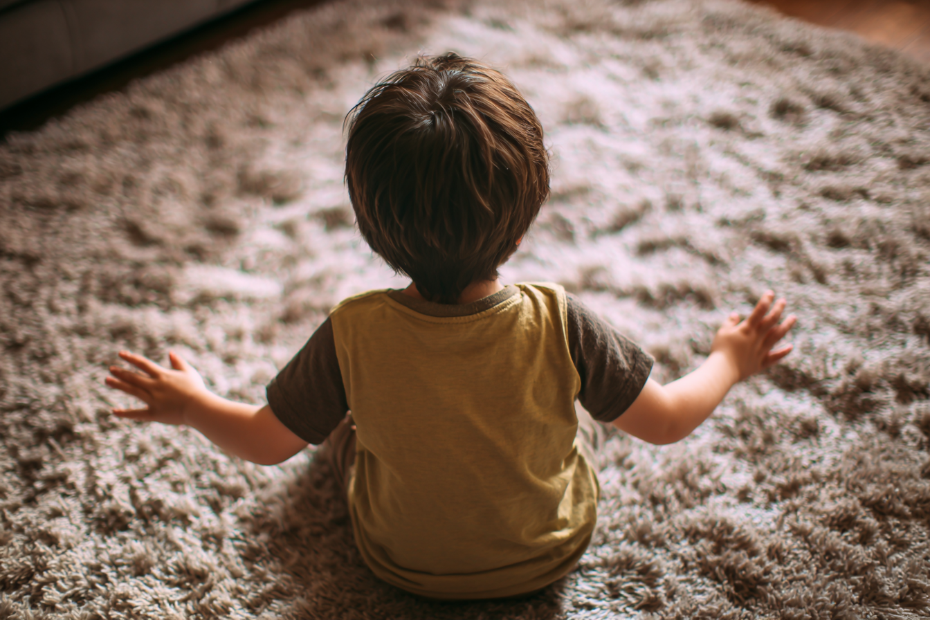Un enfant assis sur un tapis qui bat joyeusement des mains | Source : Midjourney