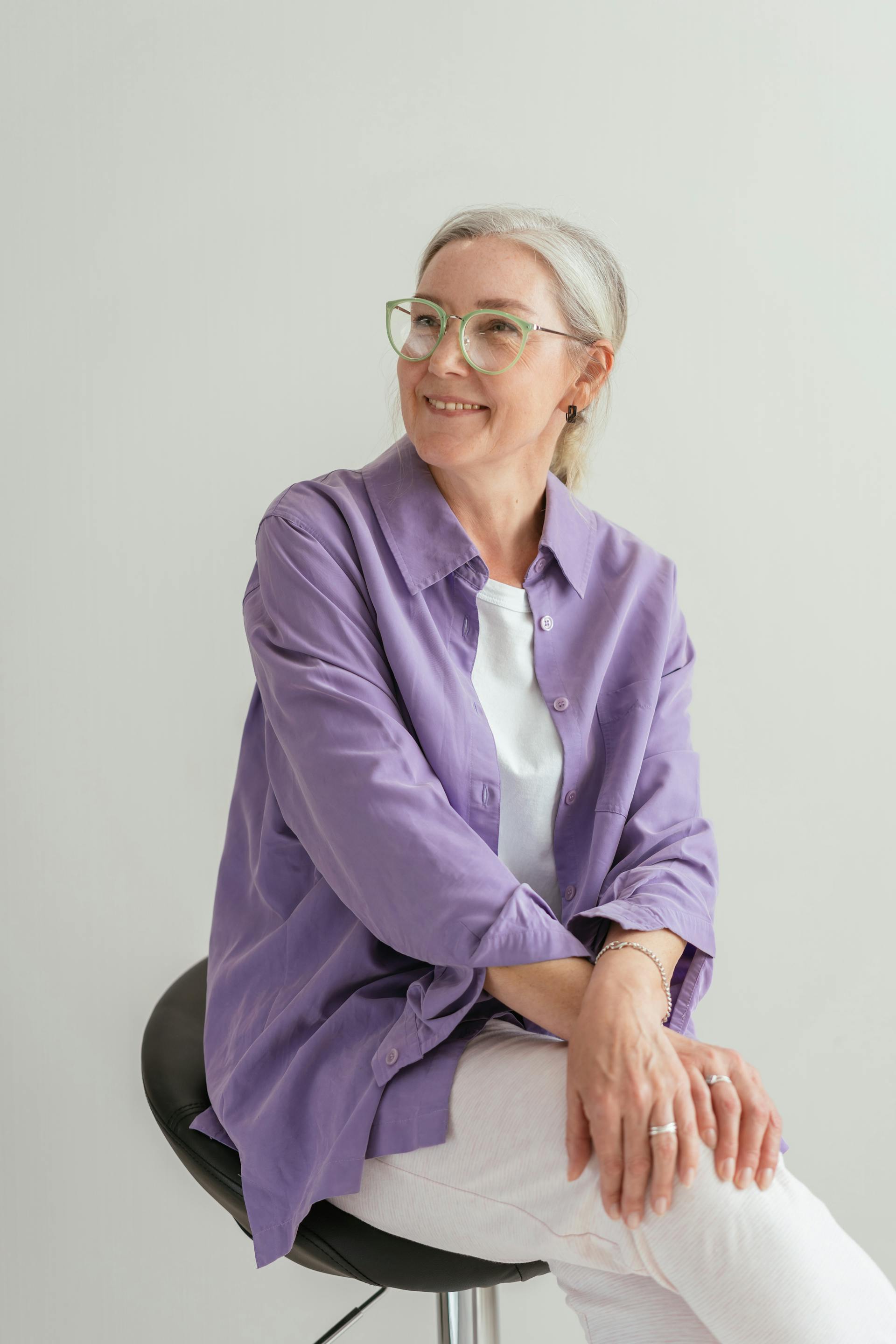 Une femme souriante assise sur une chaise noire | Source : Pexels