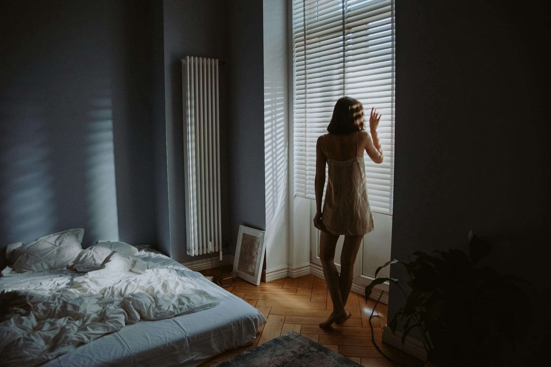 Une femme debout près des volets de la fenêtre de sa chambre | Source : Pexels
