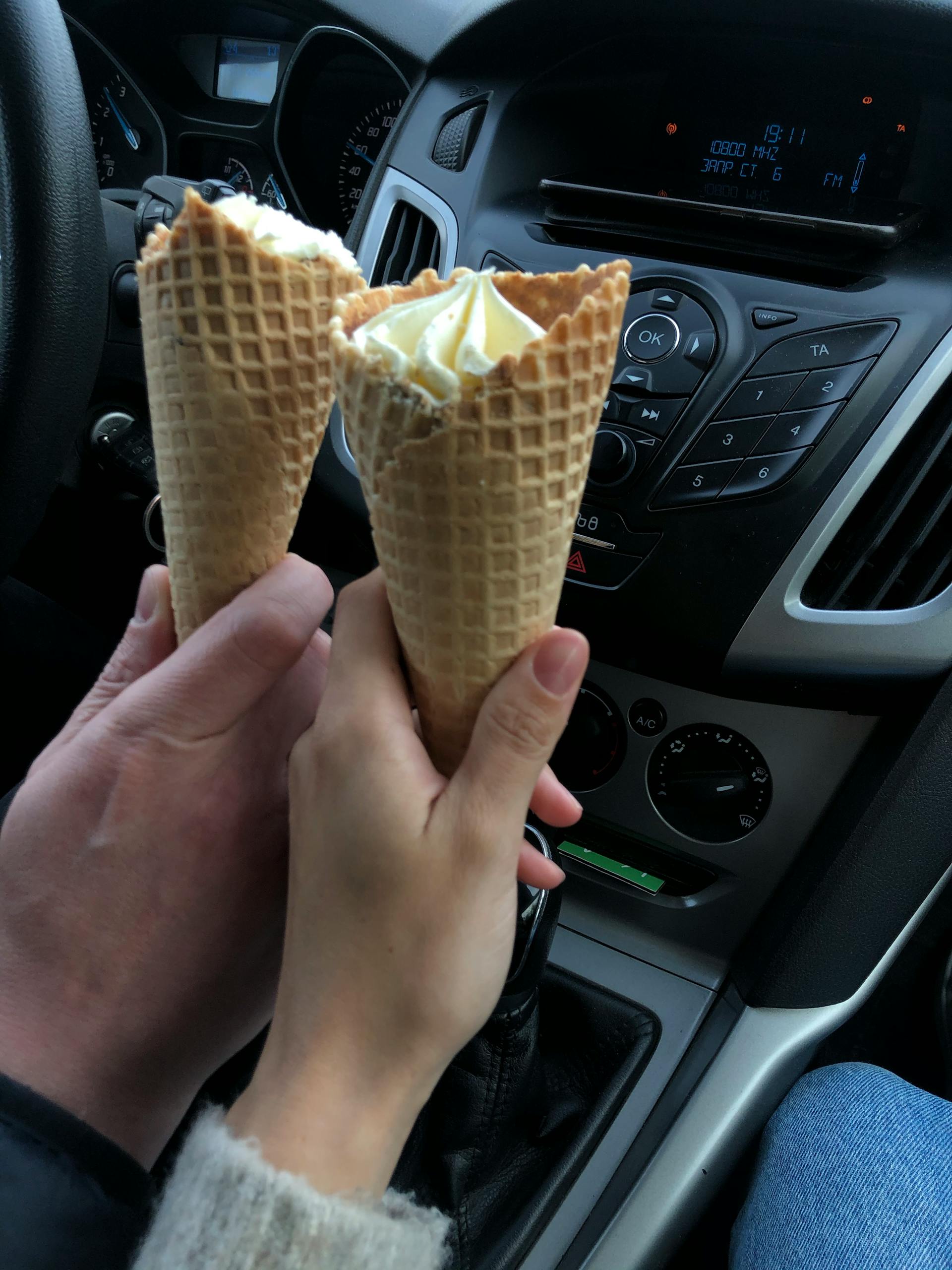 Un couple tenant des cornets de glace dans une voiture | Source : Pexels