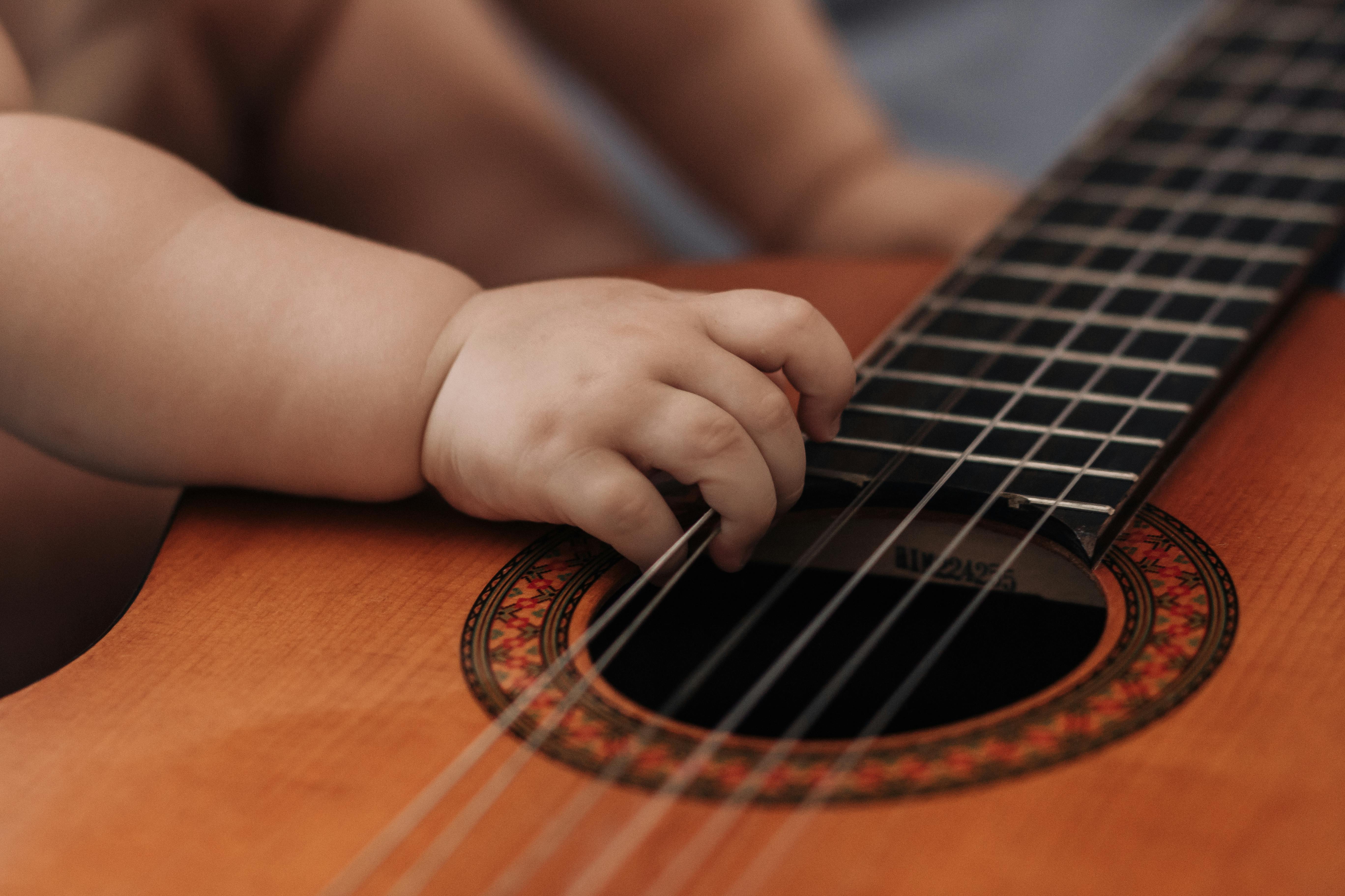 La main d'un bébé tenant les cordes d'une guitare | Source : Pexels