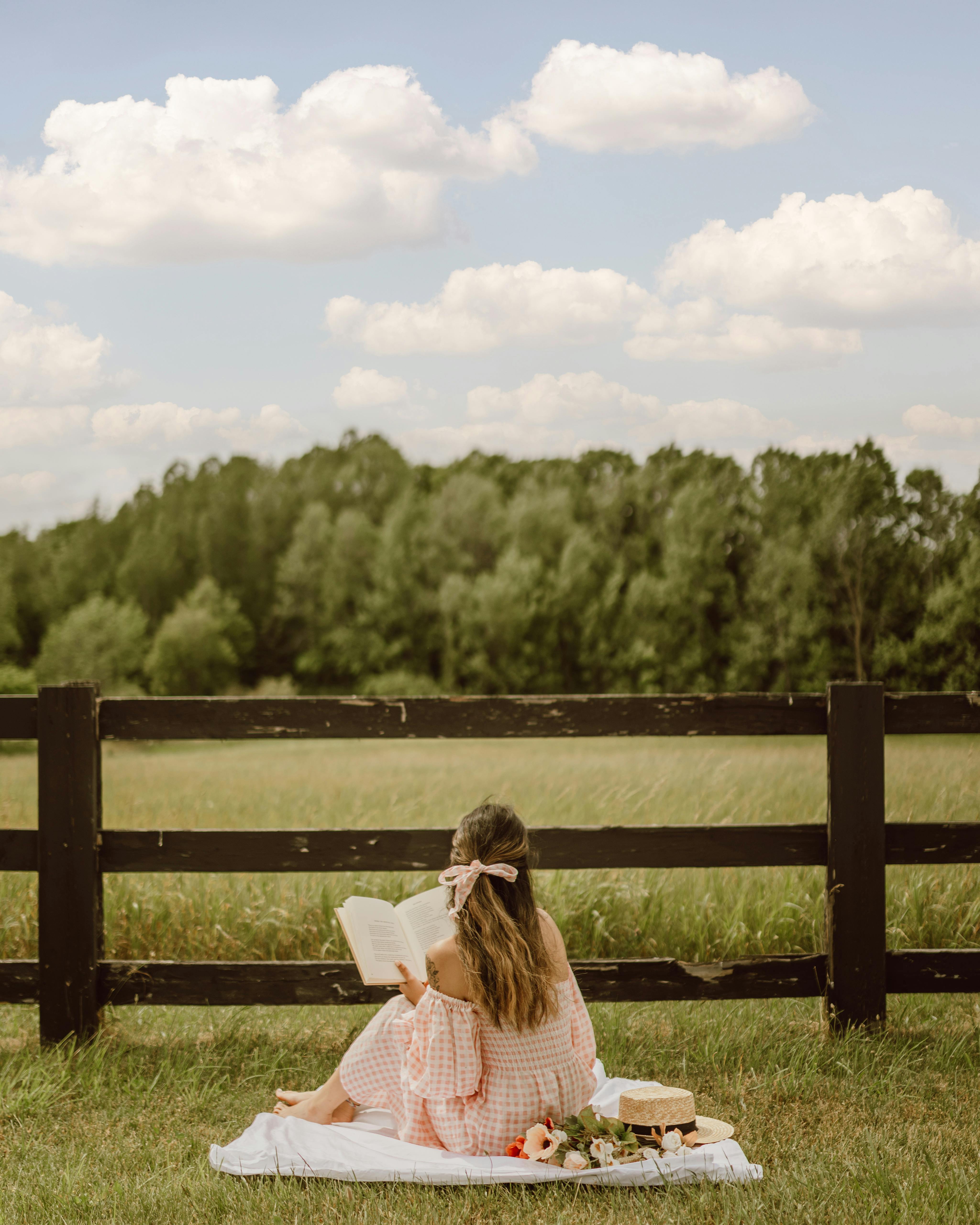 Femme profitant d'un pique-nique tout en lisant un livre | Source : Pexels