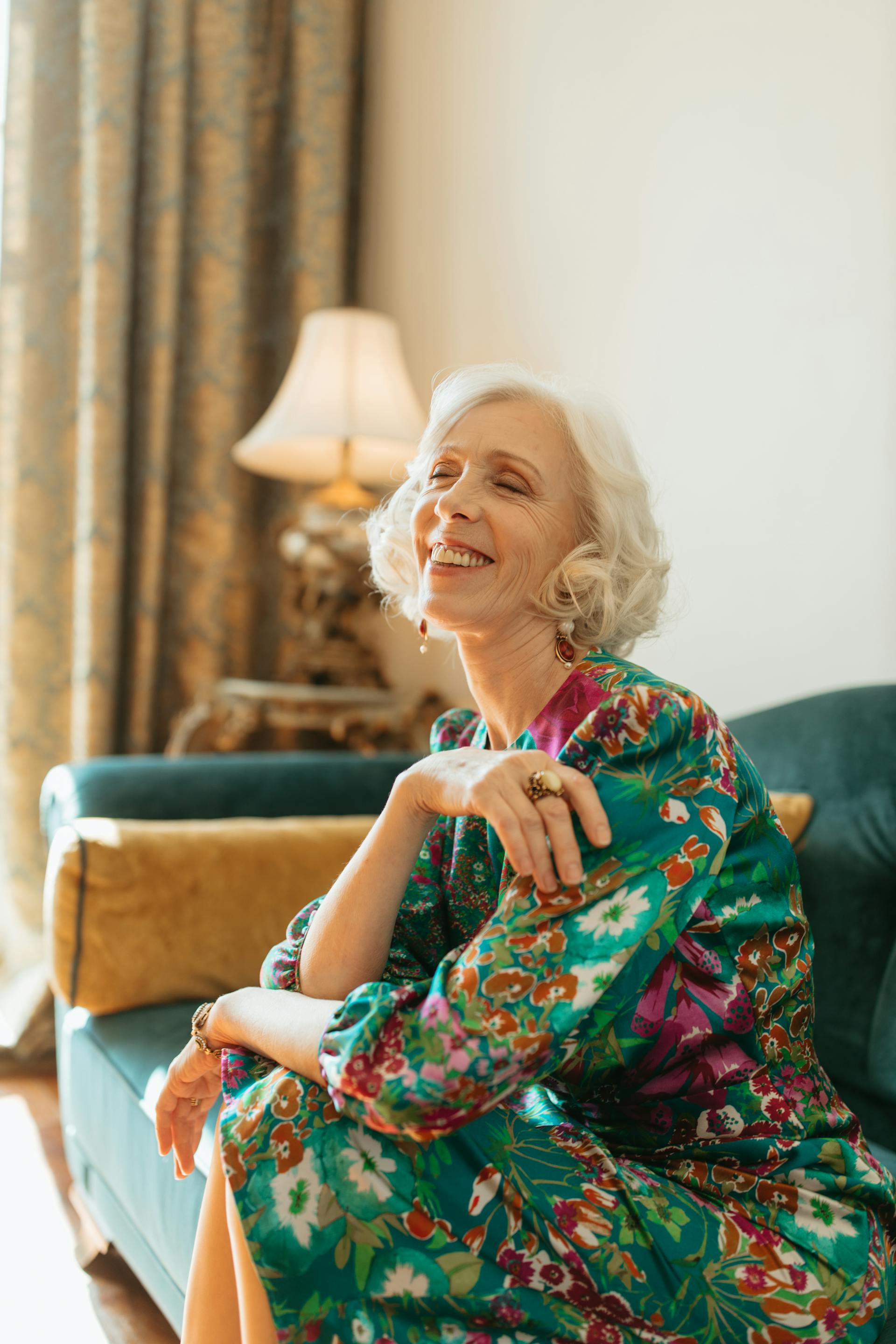 Une femme âgée assise sur le canapé et riant | Source : Pexels