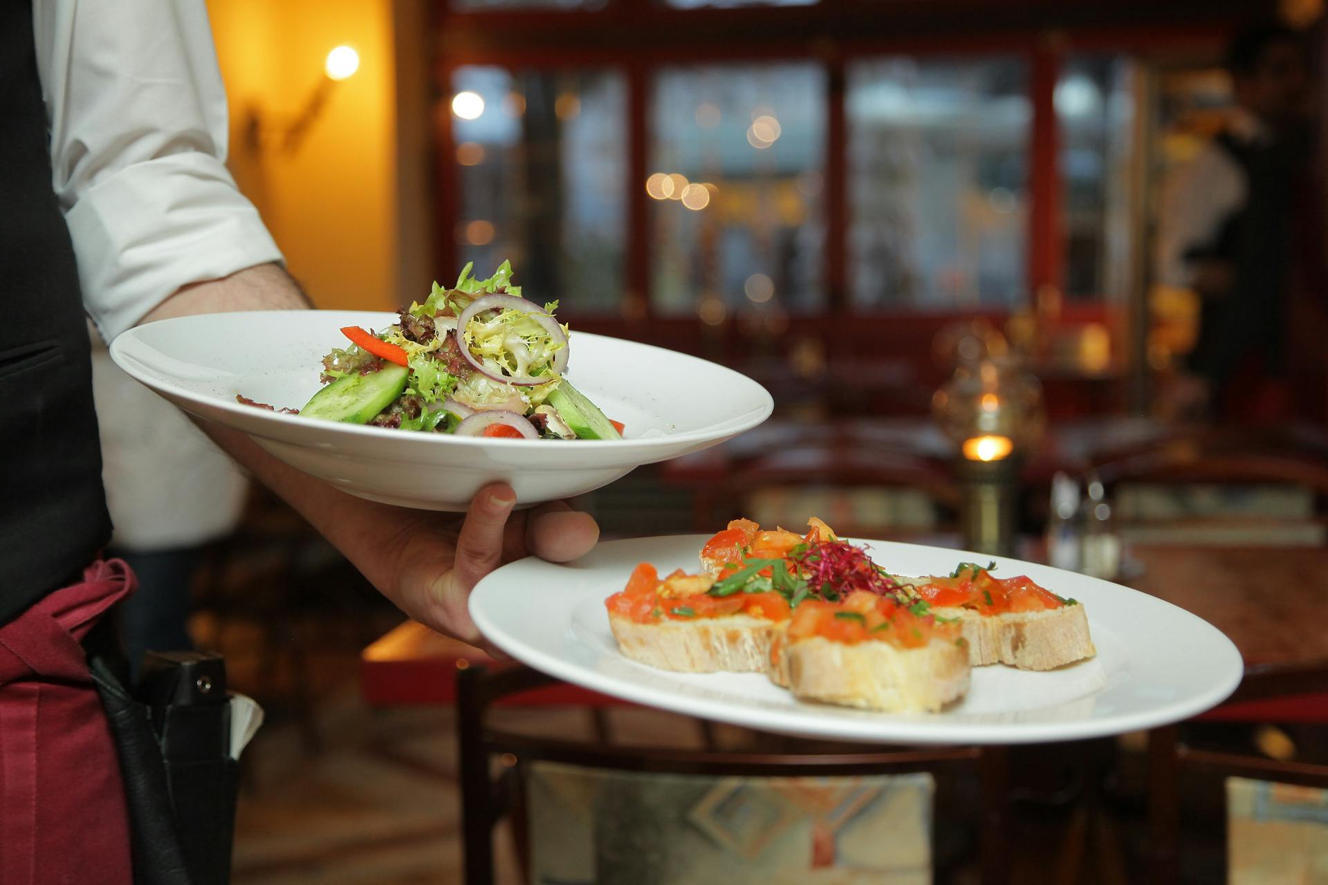 Un serveur tenant deux assiettes de nourriture | Source : Pexels