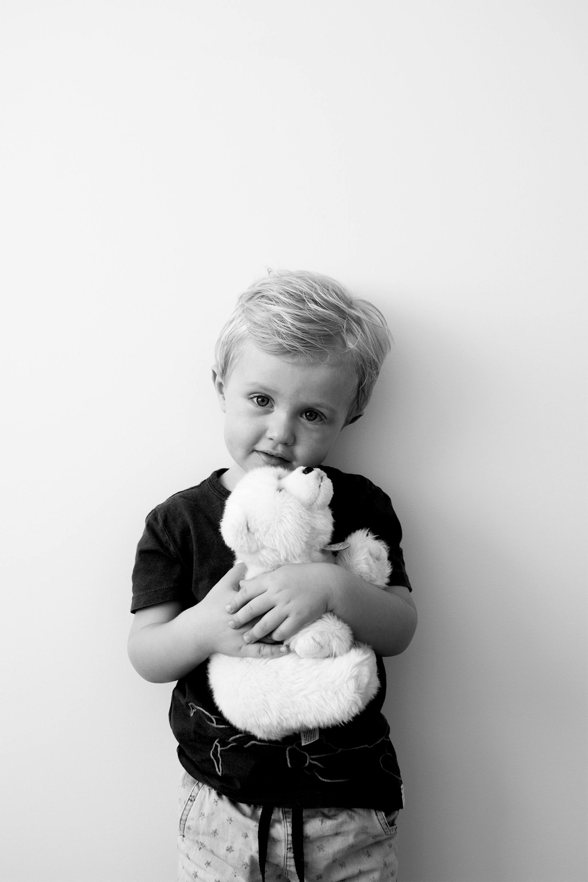 Photo en niveaux de gris d'un garçon tenant un ours en peluche | Source : Pexels