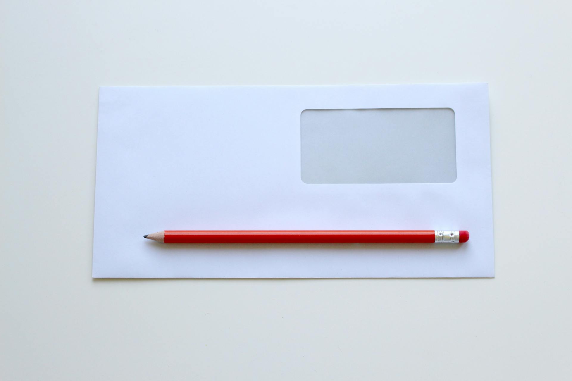 Crayon rouge posé sur une enveloppe blanche | Source : Pexels