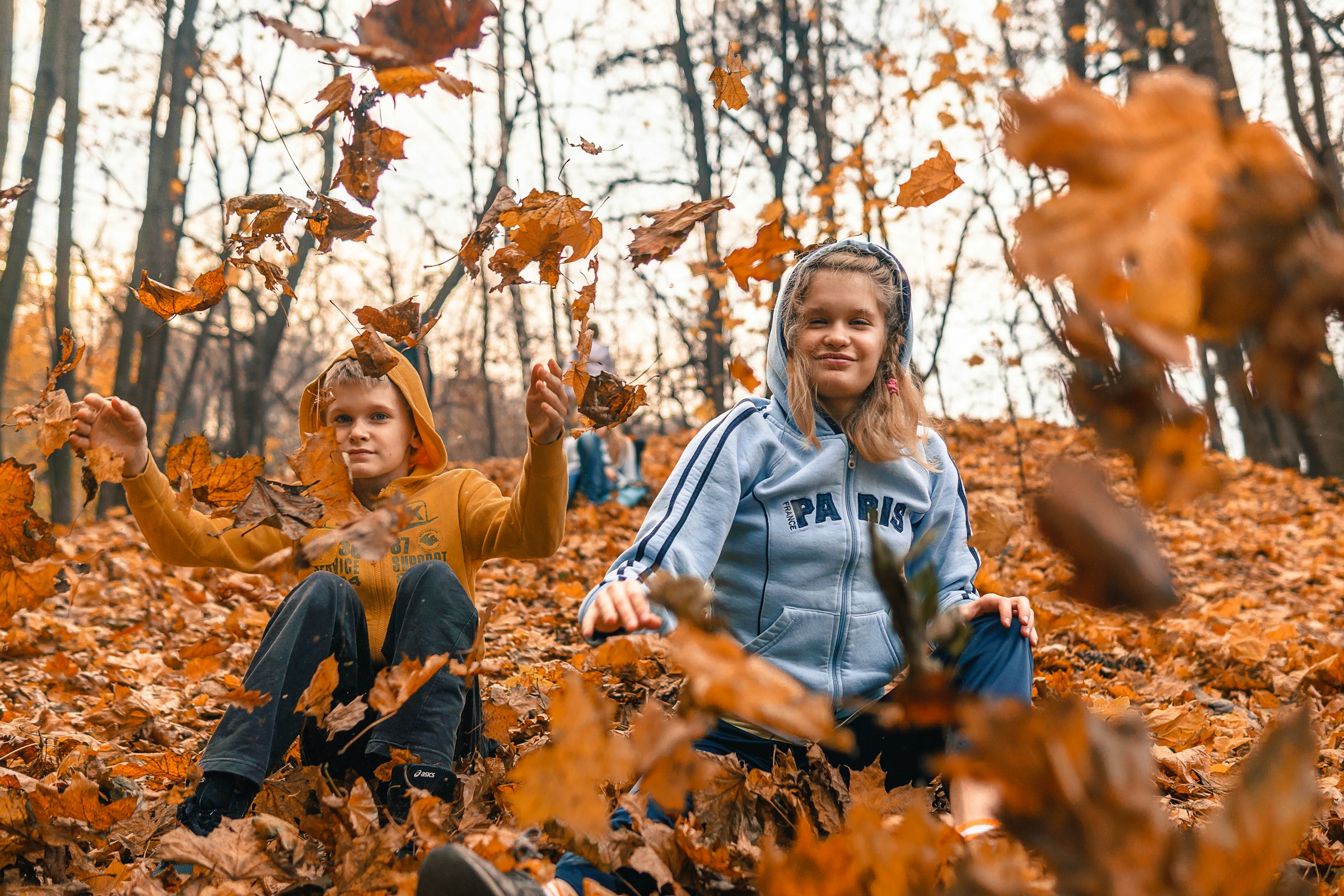 Deux enfants jouant dans des feuilles mortes | Source : Unsplash