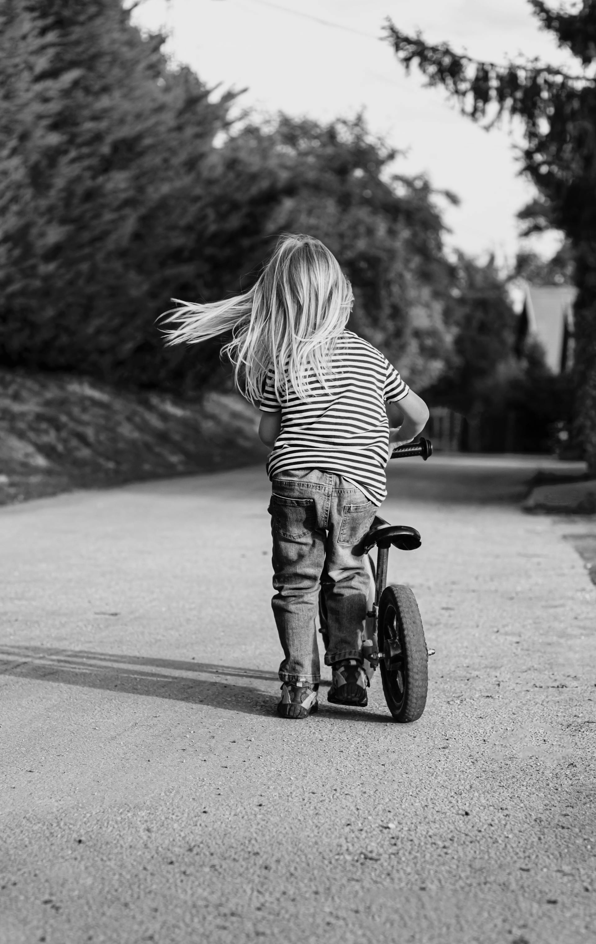 Photo en niveaux de gris d'une petite fille qui fait du vélo | Source : Pexels