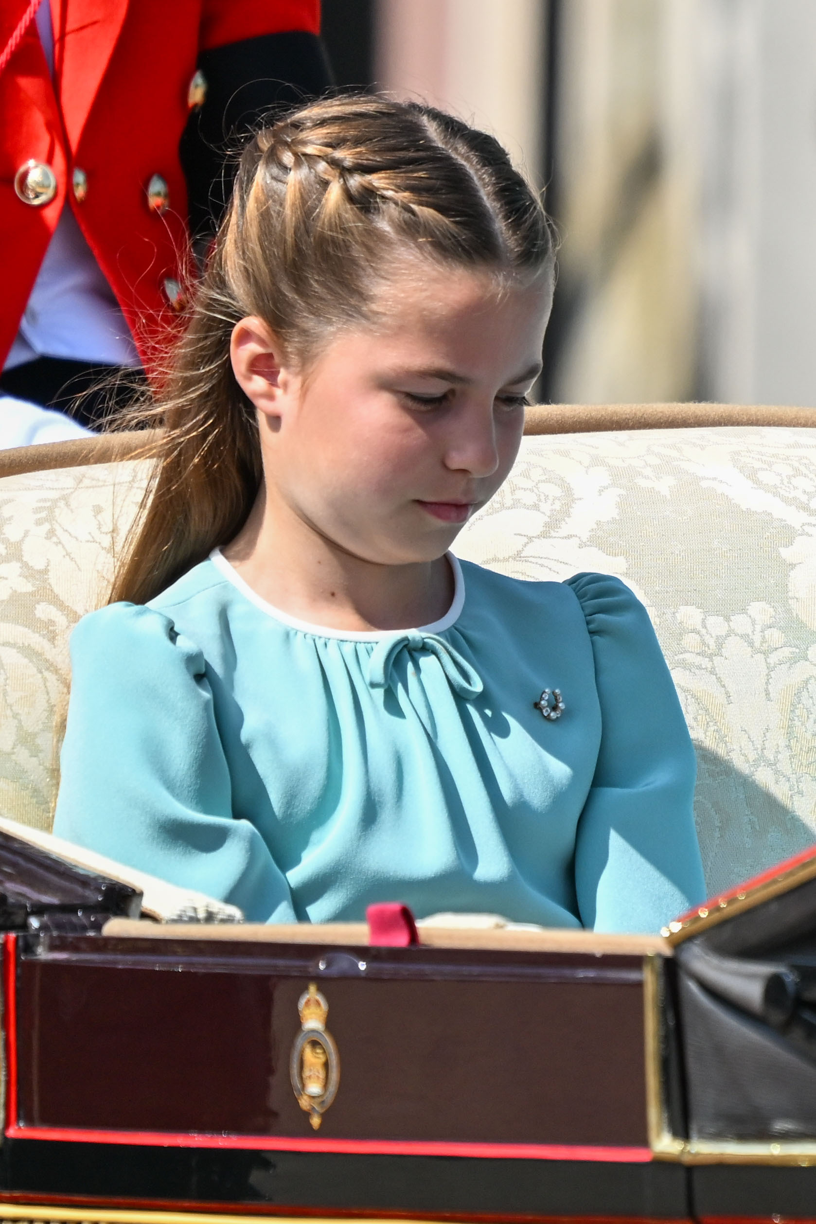 La princesse Charlotte de Galles est photographiée dans sa robe blanche et aigue-marine alors qu'elle se rend au palais de Buckingham lors du Trooping The Colour 2025 à Londres, en Angleterre, le 14 juin 2025. Elle arbore un beau sourire et met l'internet en ébullition avec ses longs et épais cheveux bruns, portés détachés avec une raie centrale soignée.