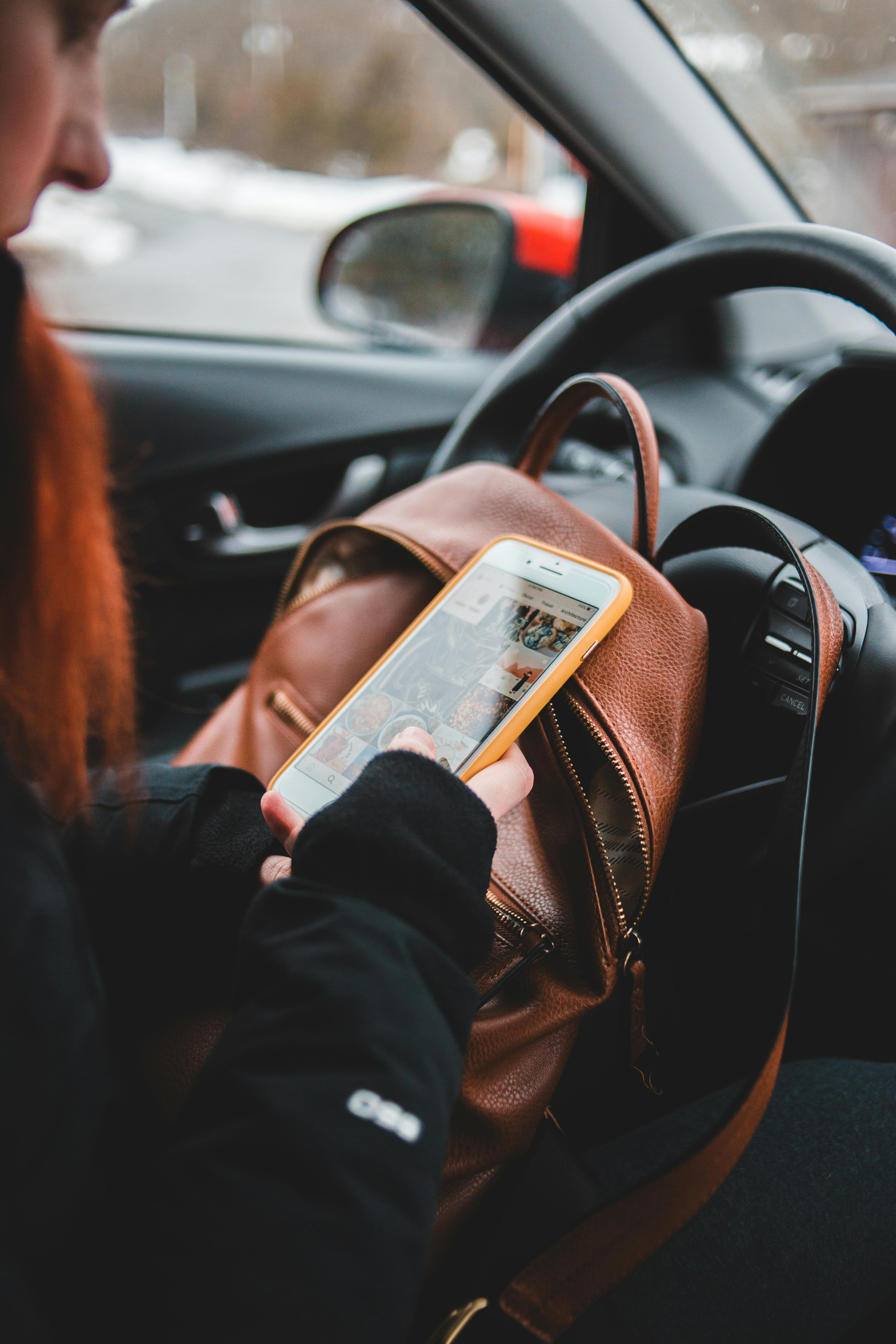 Une femme qui vérifie son téléphone dans une voiture | Source : Pexels