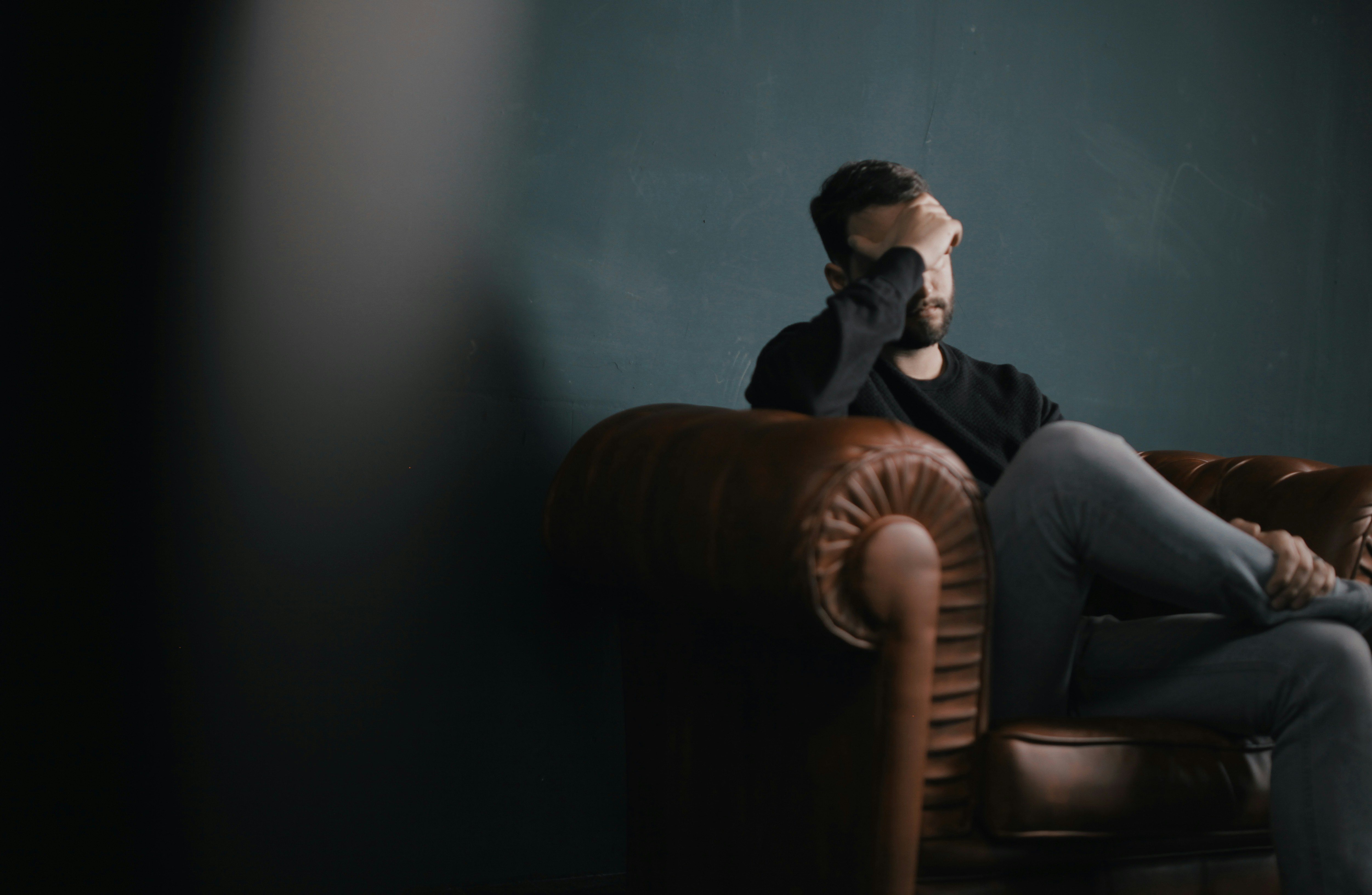 Un homme stressé assis sur un canapé | Source : Unsplash