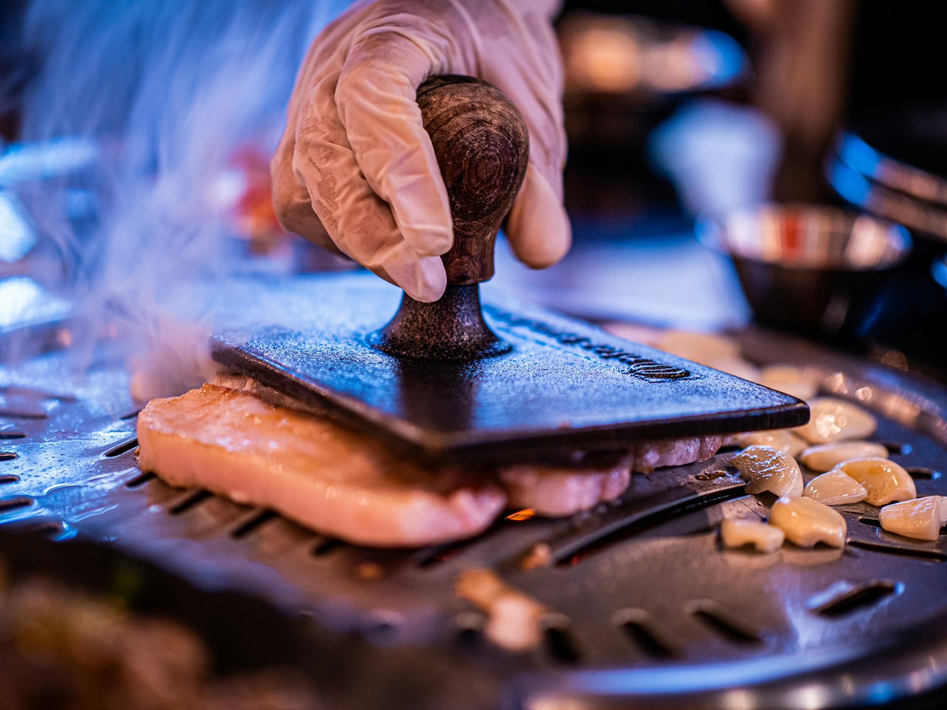 Une personne portant un gant fait griller de la viande | Source : Pexels