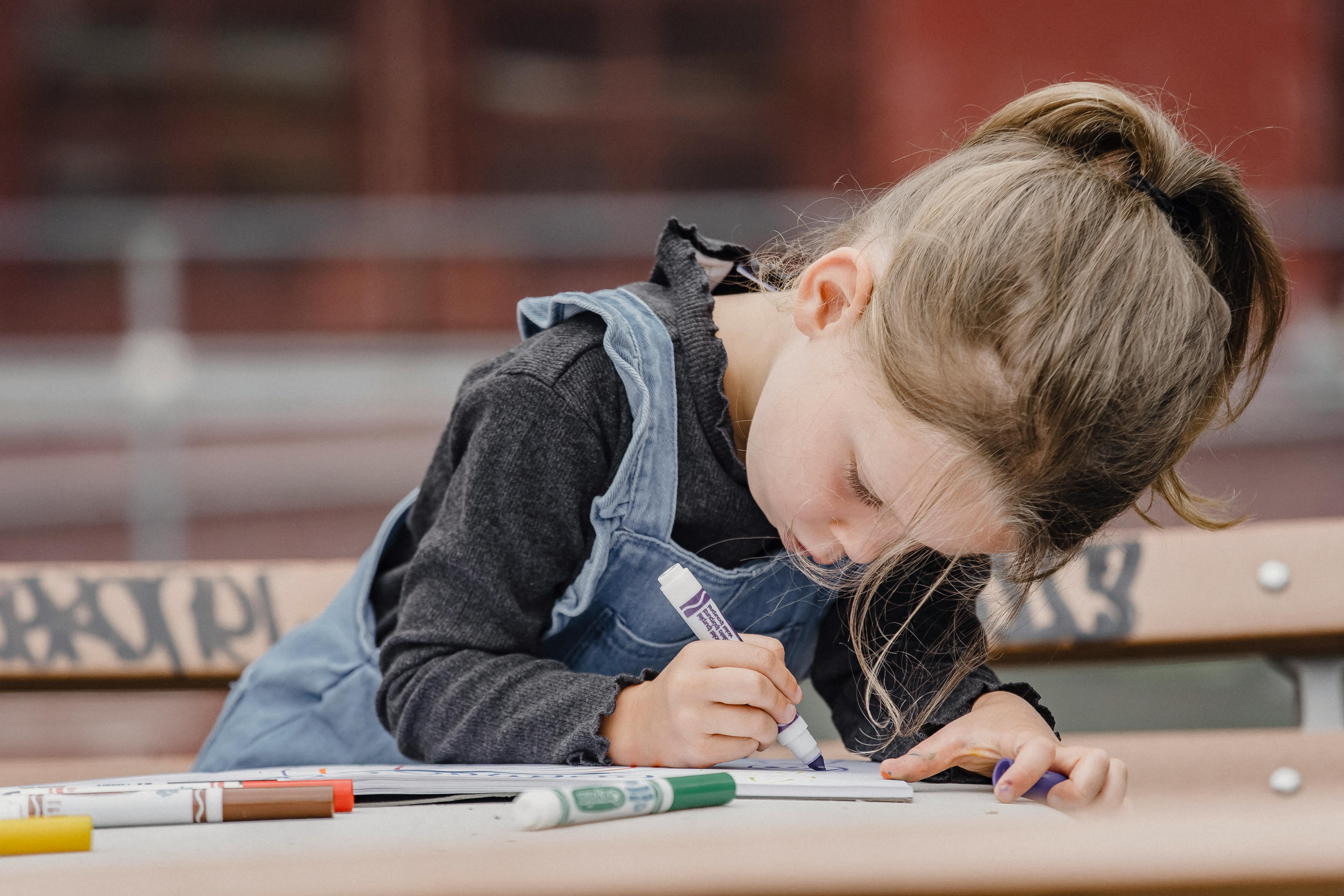 Une petite fille en train de colorier dans son livre | Source : Pexels