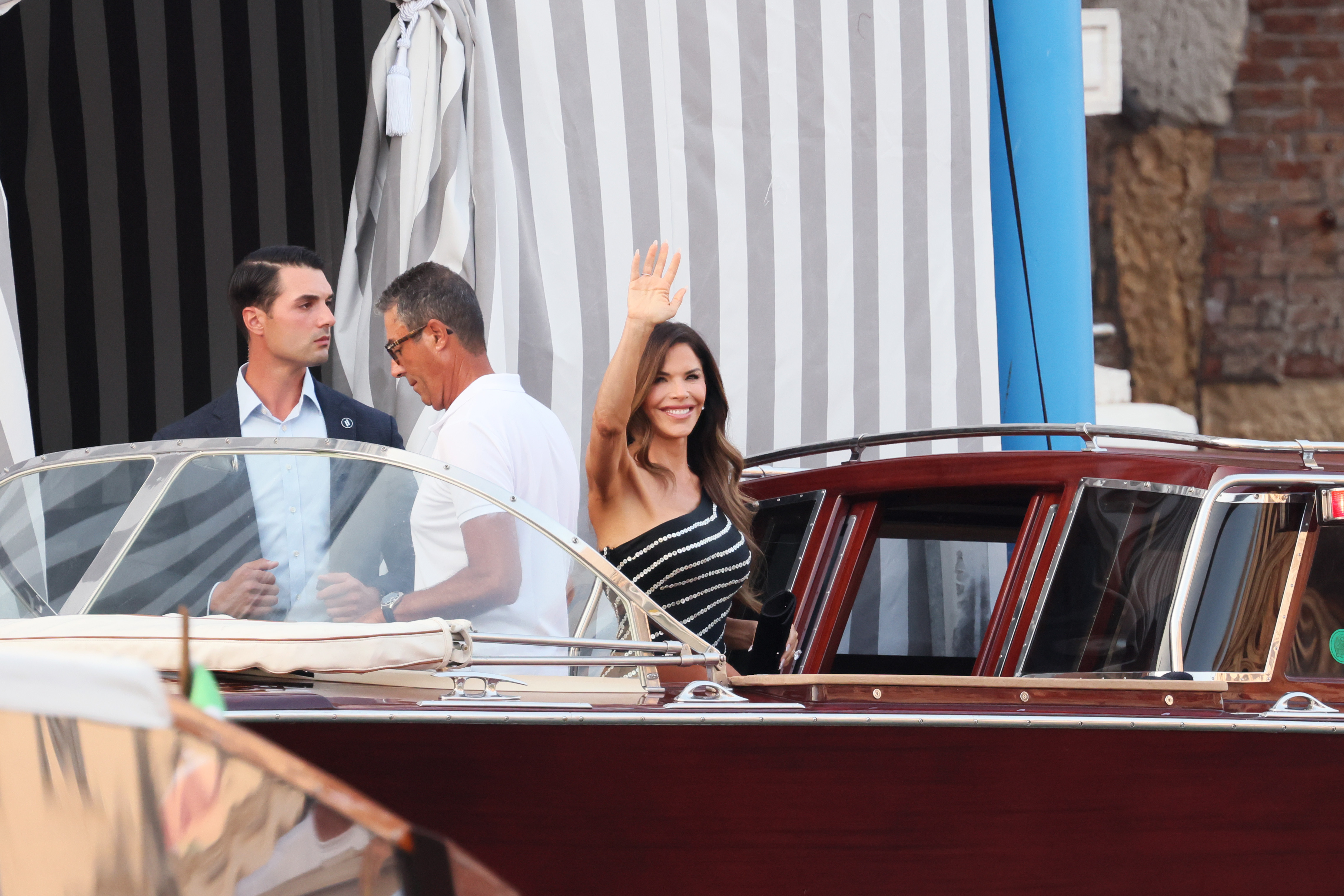 Lauren Sanchez sourit et fait un signe de la main alors qu'elle se prépare à monter à bord d'un bateau à l'extérieur de l'hôtel du couple à Venise, en Italie, le 25 juin 2025 | Source : Getty Images